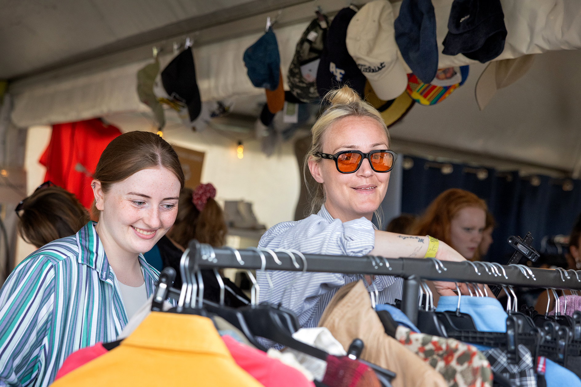 Foto: Av to kvinner som står over et klesstativ med brukte kjær.