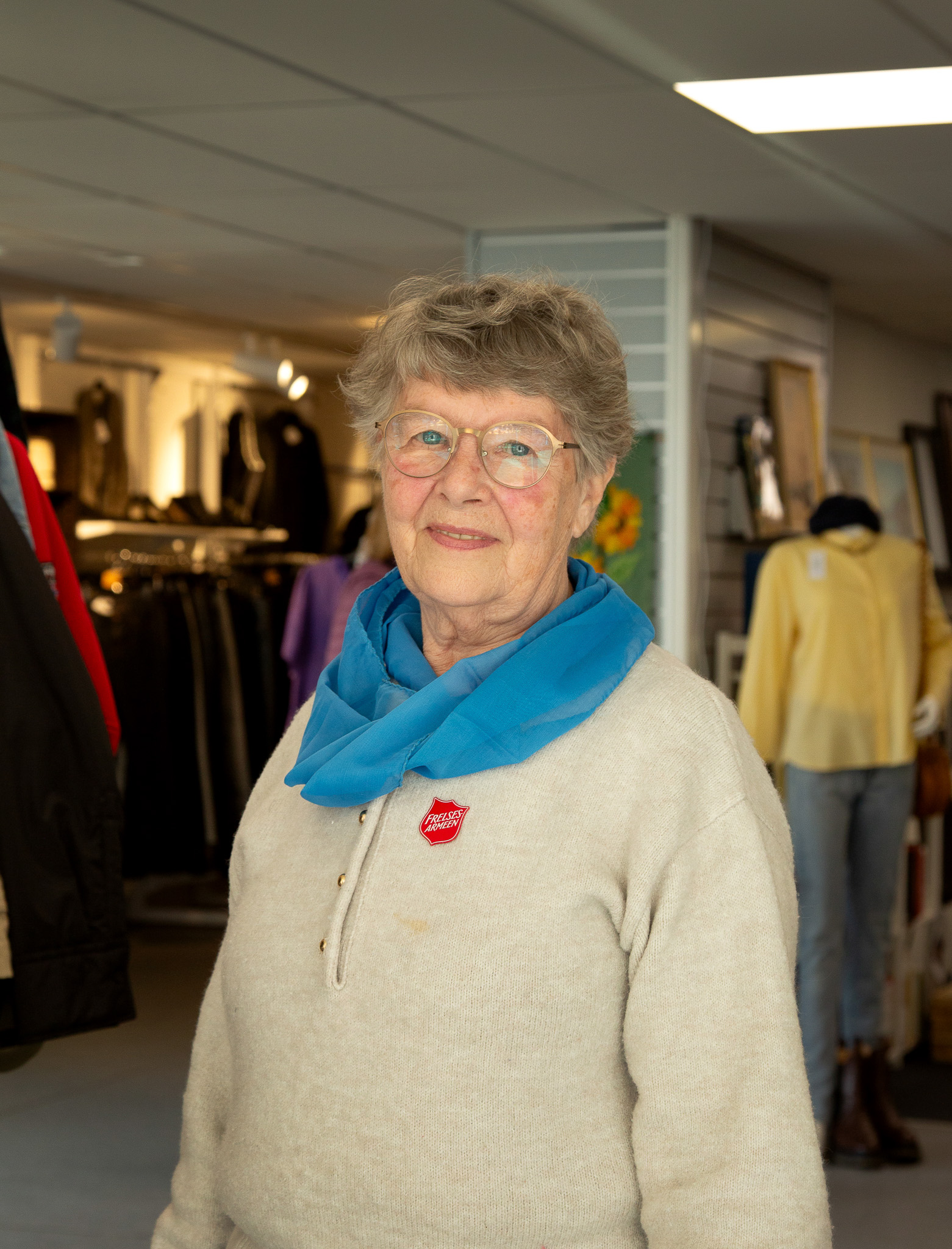 Kvinne i lys genser med blått skjerf rundt halsen