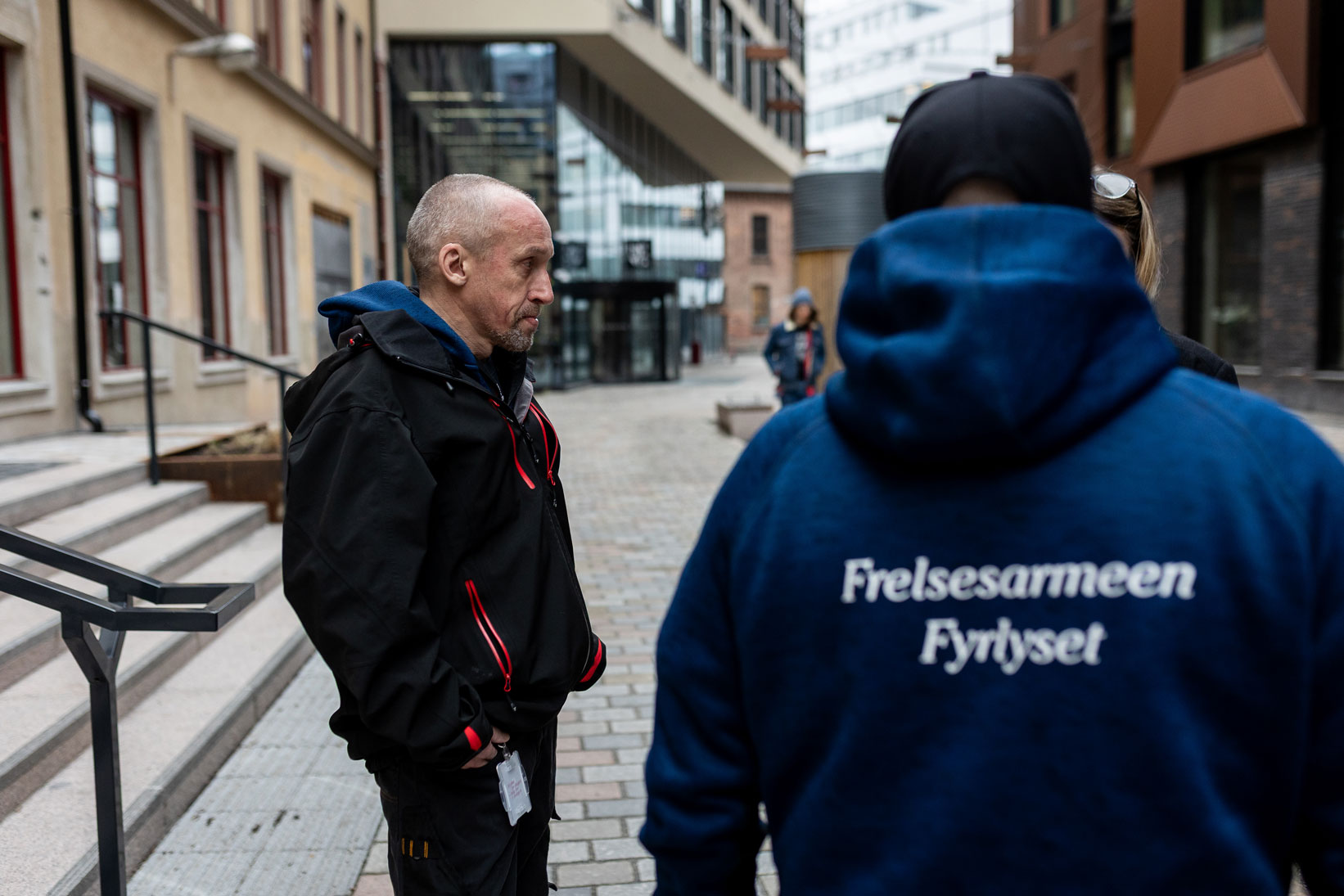 Foto: To bilder der vi vekselsvis ser ansiktet til de to sosiale vaktmestrene Jørn og Yannick. VI ser at de er omgitt av nye høyblokker.