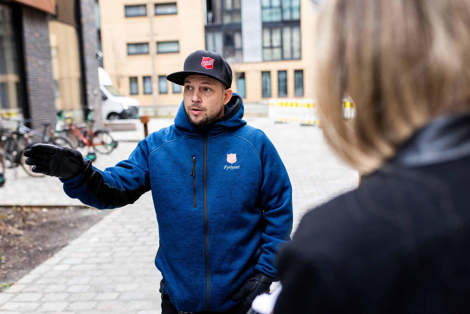 Foto: To bilder der vi vekselsvis ser ansiktet til de to sosiale vaktmestrene Jørn og Yannick. VI ser at de er omgitt av nye høyblokker.