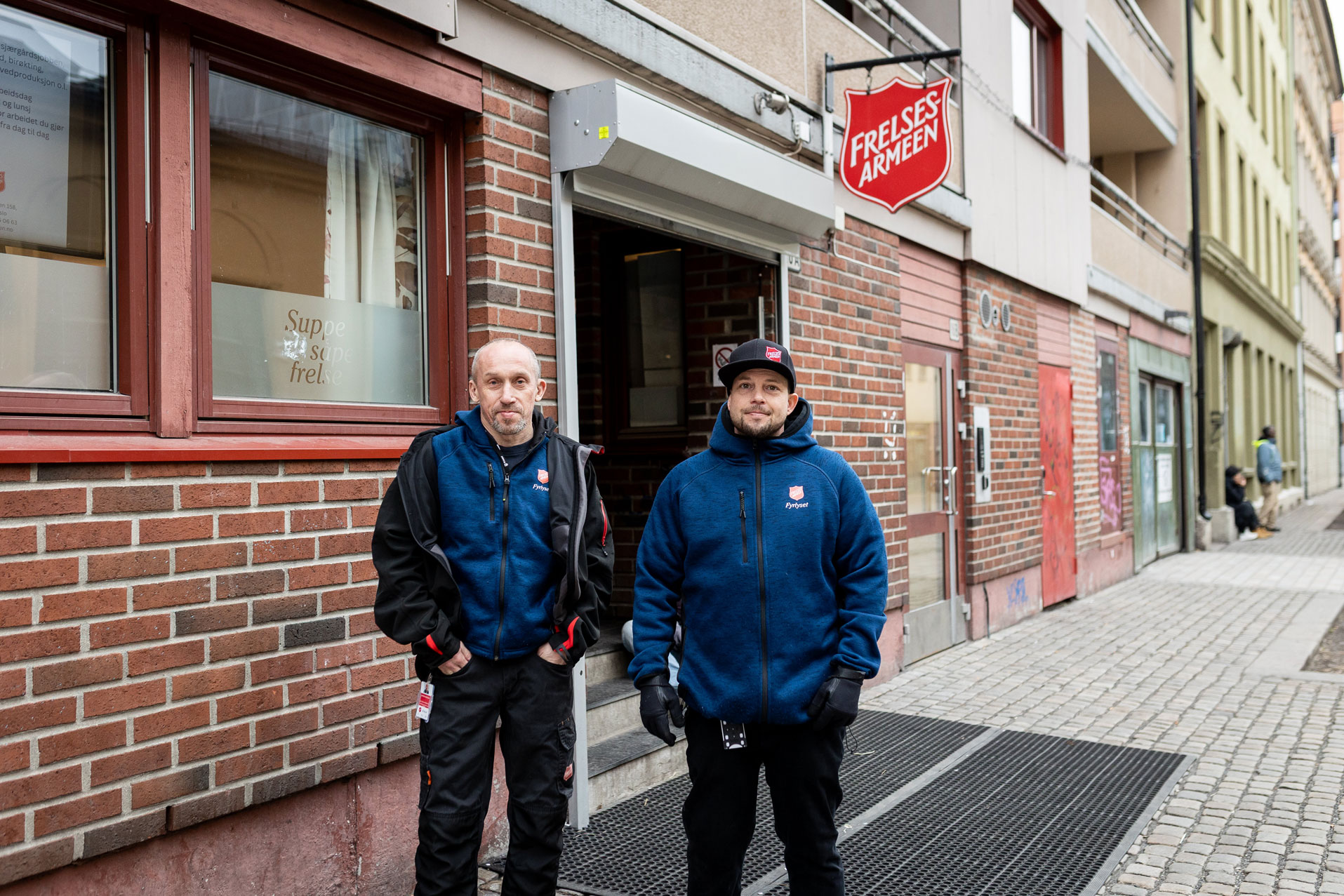 Foto: To menn som står på gaten. I bakgrunnen henger et skilt fra Frelsesarmeen.