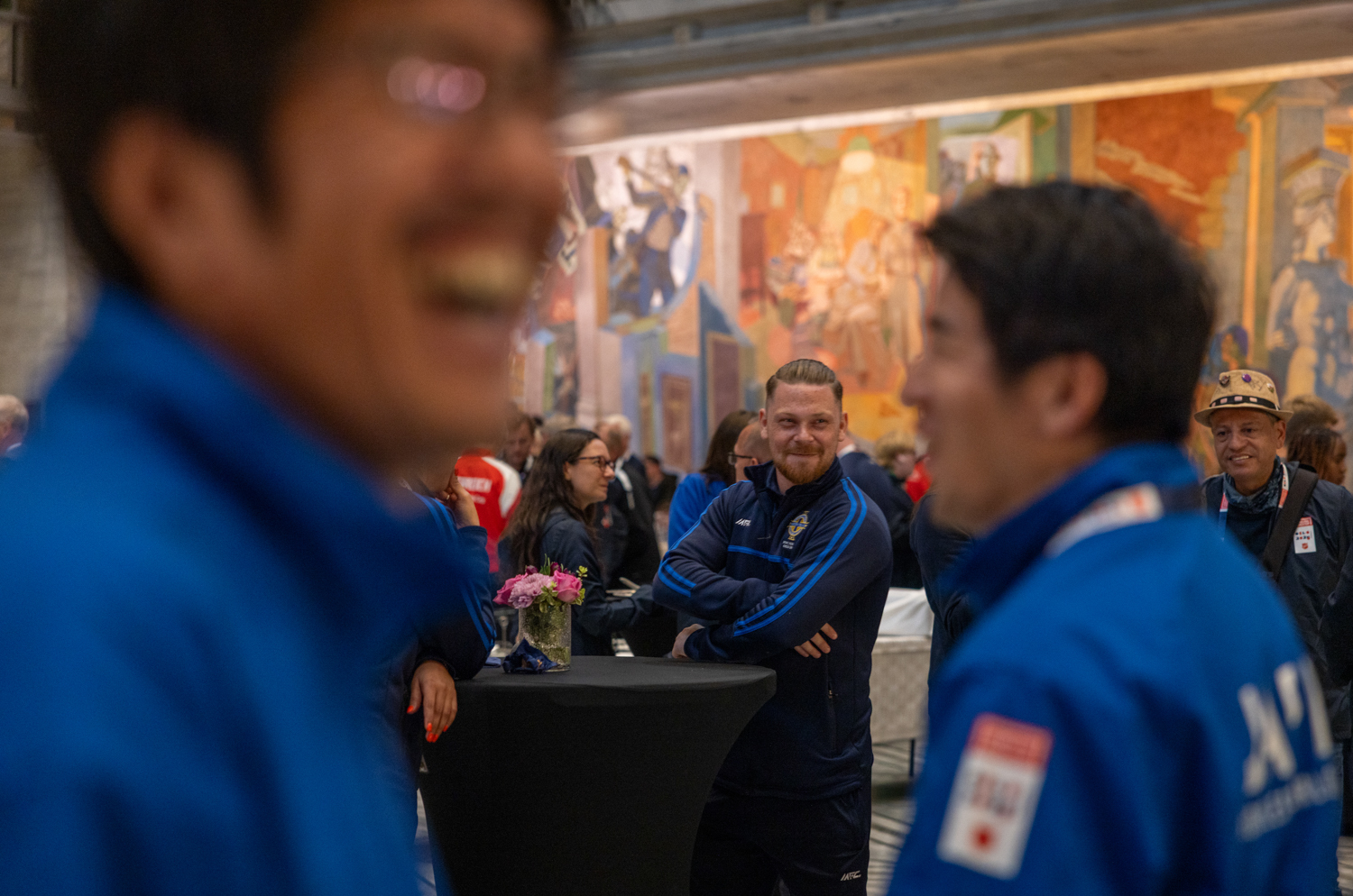 Foto: Smilende og glade folk inne i den store rådhussalen med sine veggmalerier.