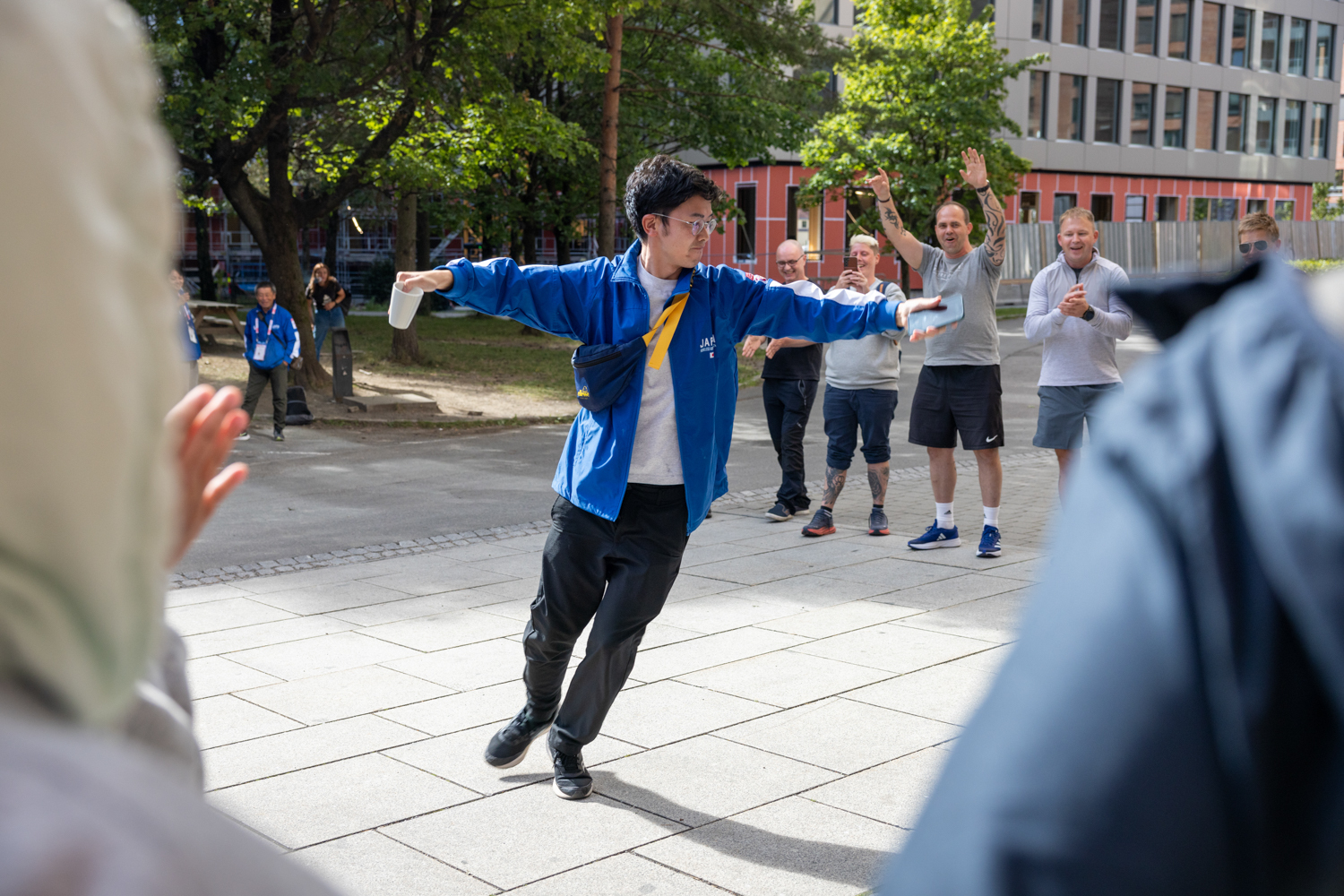 Foto: En ung mann med asiatisk utseende og briller danser foran rekker av klappende nordmenn.