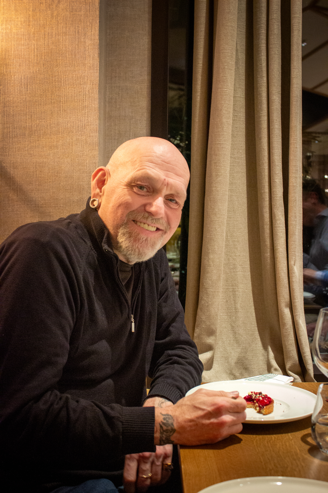 Mann uten hår med litt skjegg spiser dessert på restaurant.