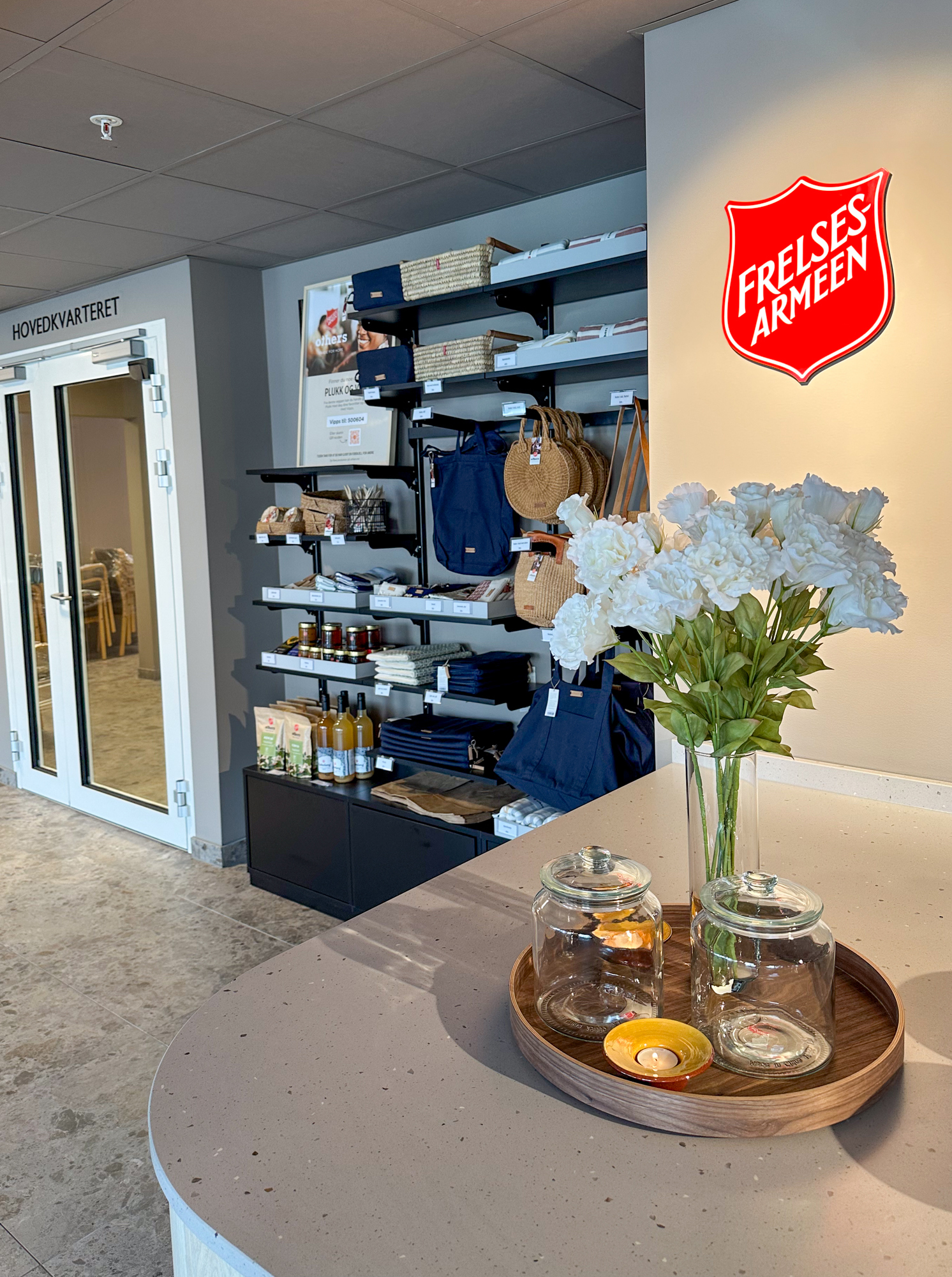 Foto: Bilde fra enden av disken der en ser på hyllene med ting til salgs. Her er også Frelsesarmeens logo stor veggen.