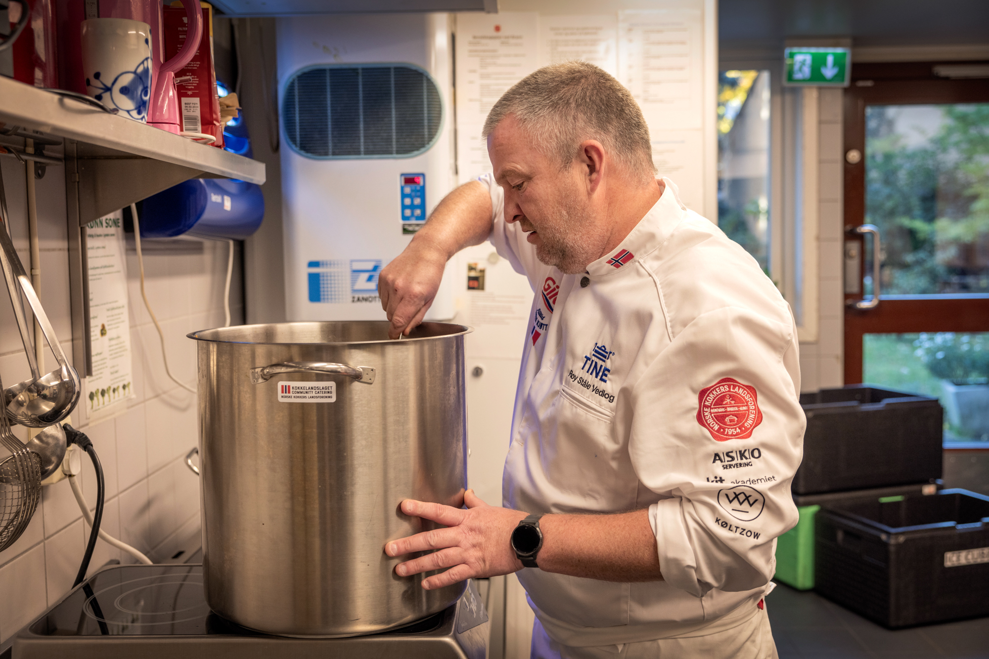 mannlig kokk som rører i en diger gryte.