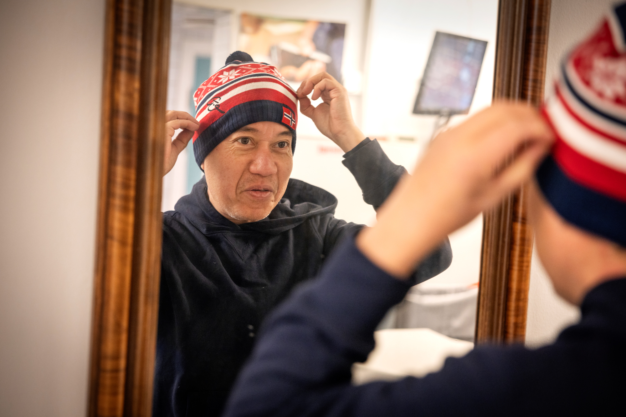 Matt som ser seg i speilet mens han prøver på en topplue i rødt, hvitt og blått.