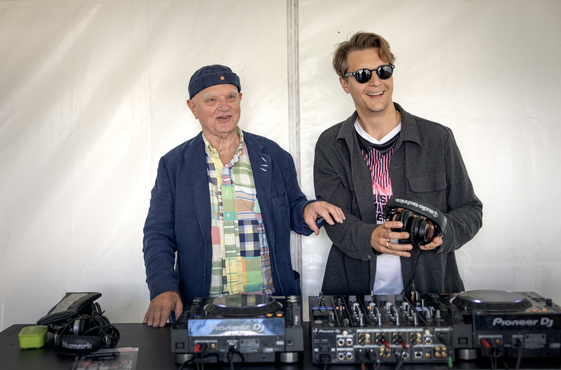 Foto: Mann i 70-årene står sammen med en mann i 30-årene ved en DJ-pult i et telt.