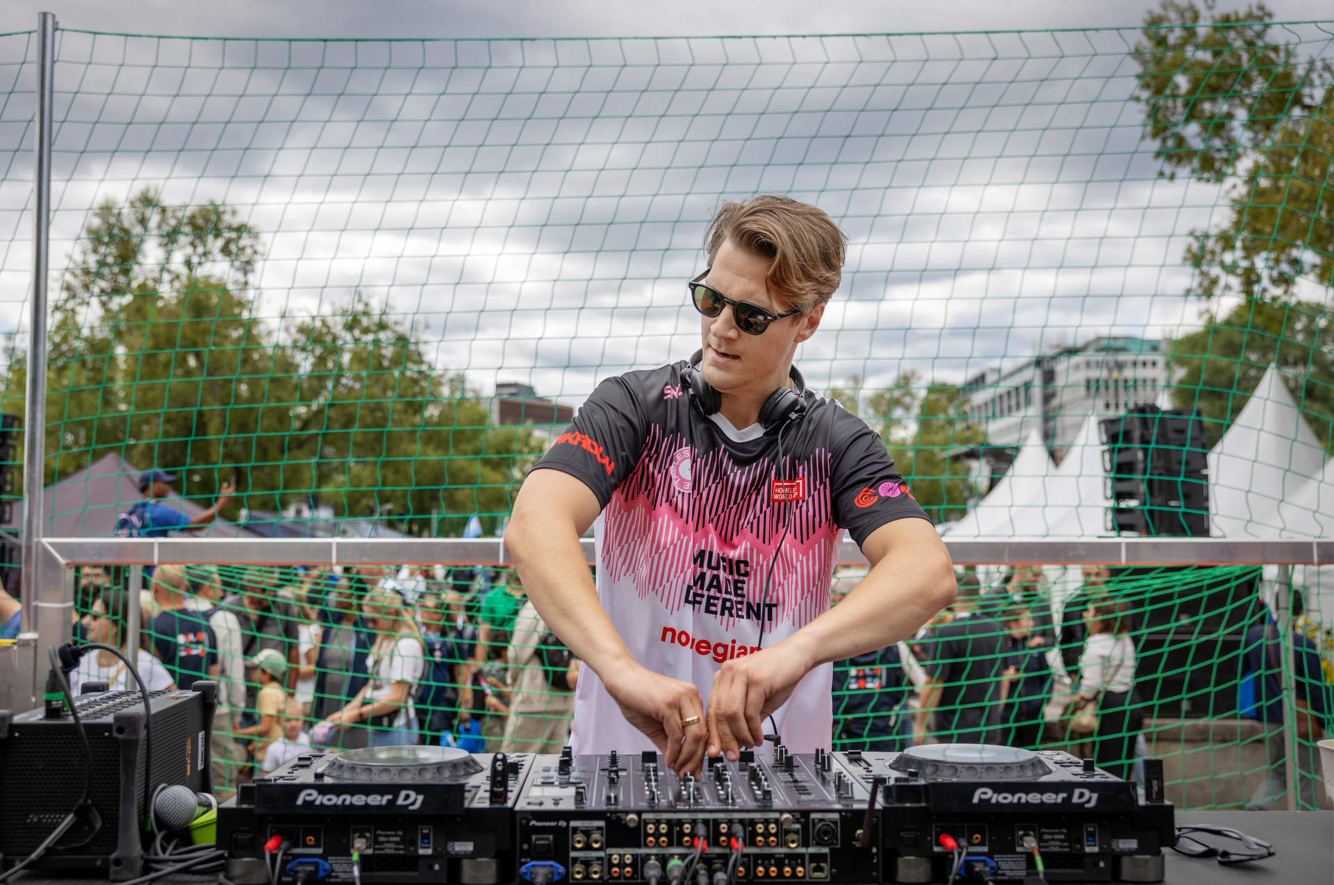 Foto: Mann bruker begge hendene på å skru knotter. Han står bak en miksepult og har på solbriller.