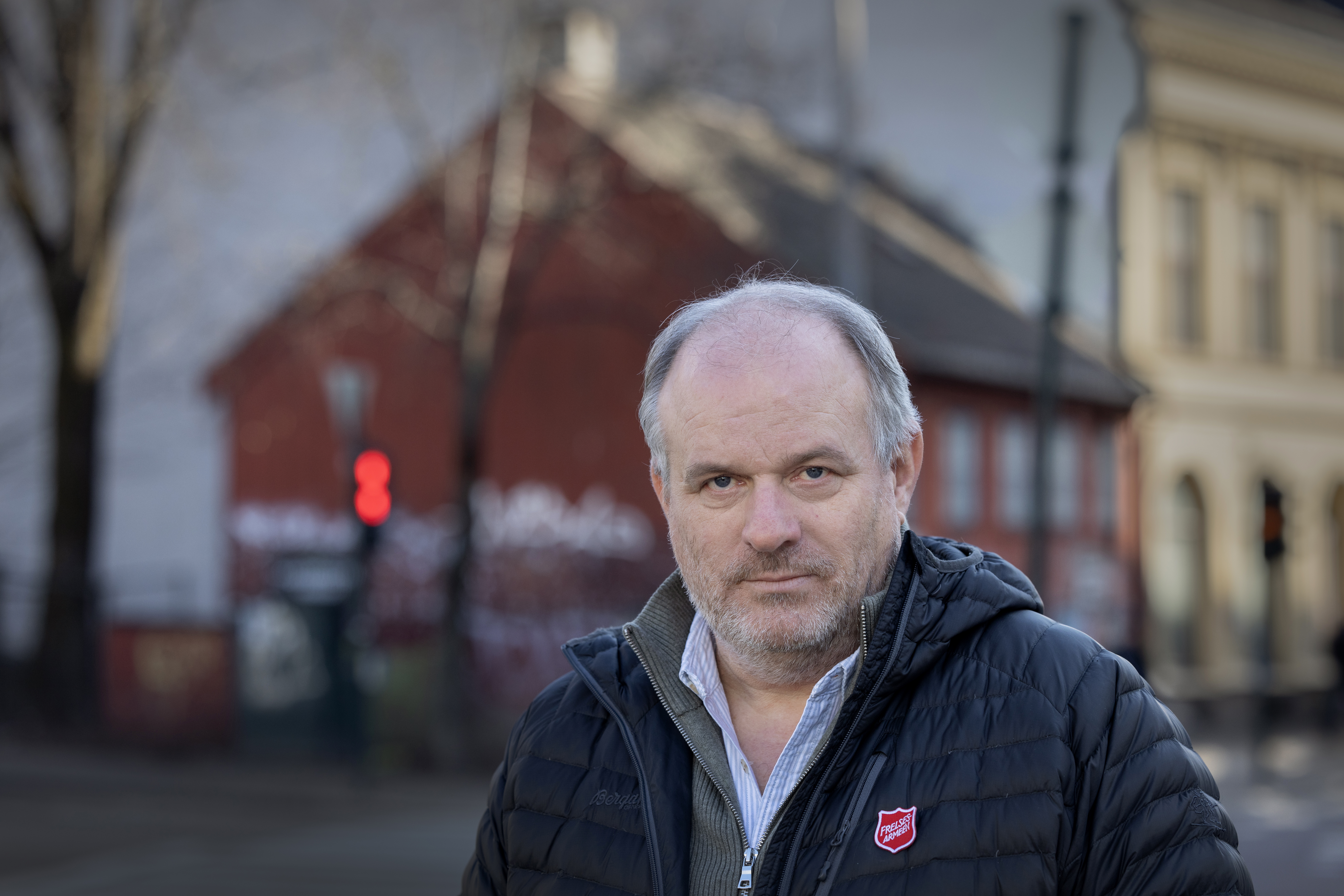 Foto: Mann i 60årene med blå boblejakke fra Frelsesarmeen står ute i bybildet i Oslo. han har grått hår og litt skjeggtuster.