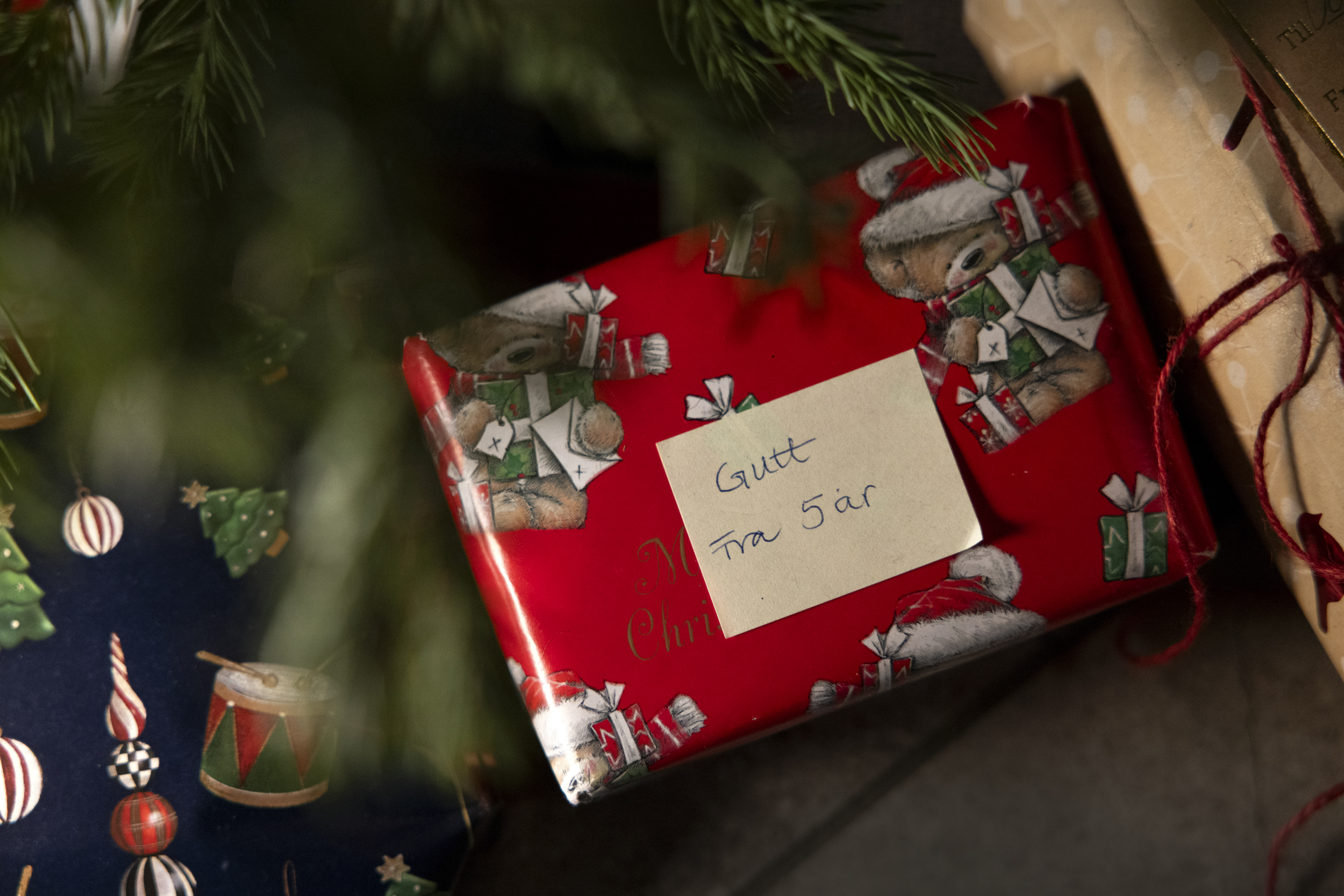 Nærbilde av julegave under et tre der det står: Gutt fra fem år.