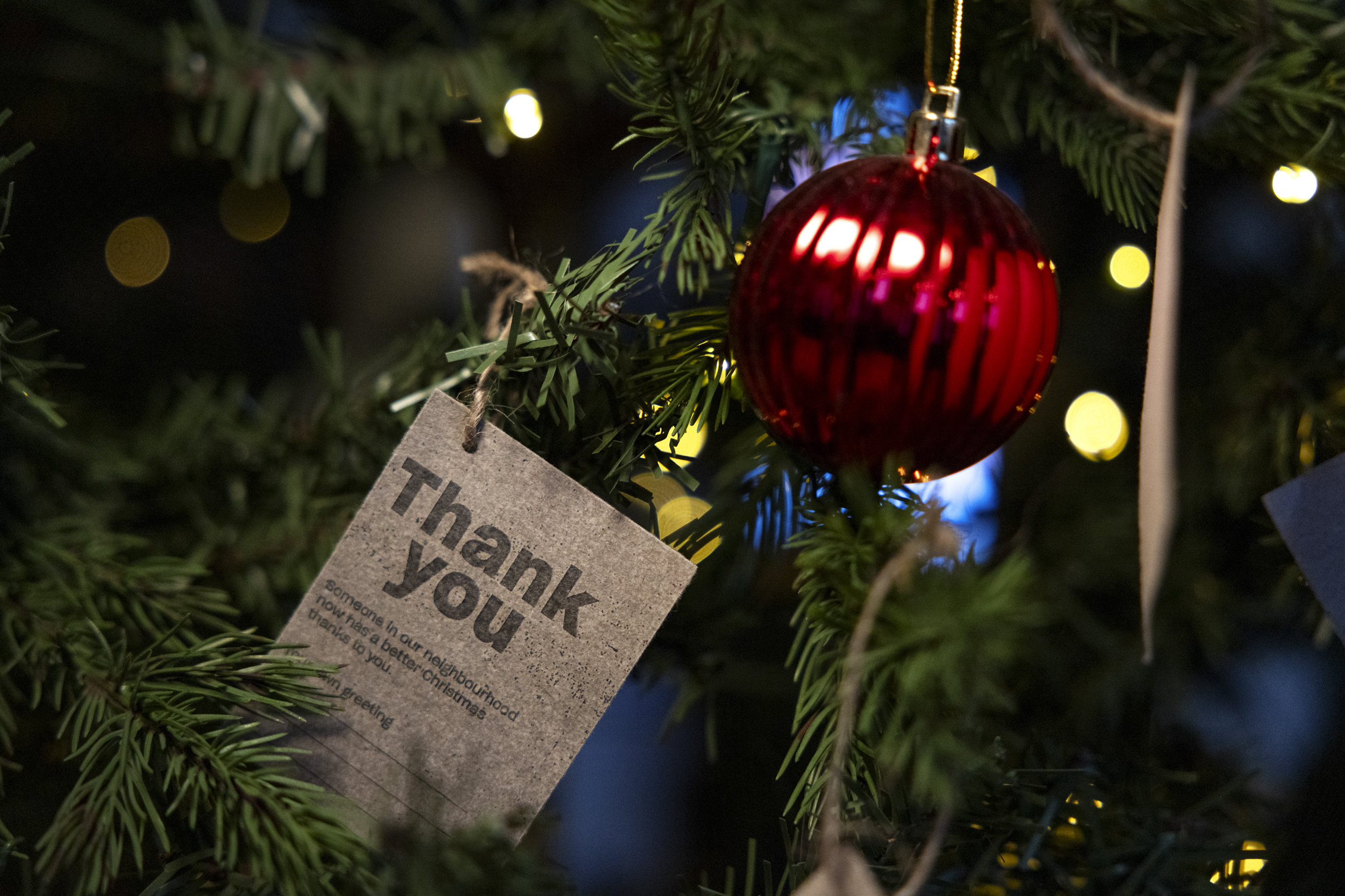 Nærbilde av en julekule som henger på treet sammen med en lapp på gråpapir der det står: Thank you!