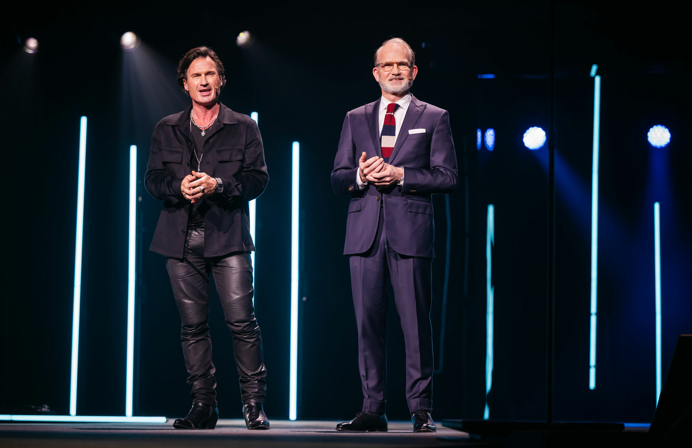 To voksne menn står på en mørk scene.