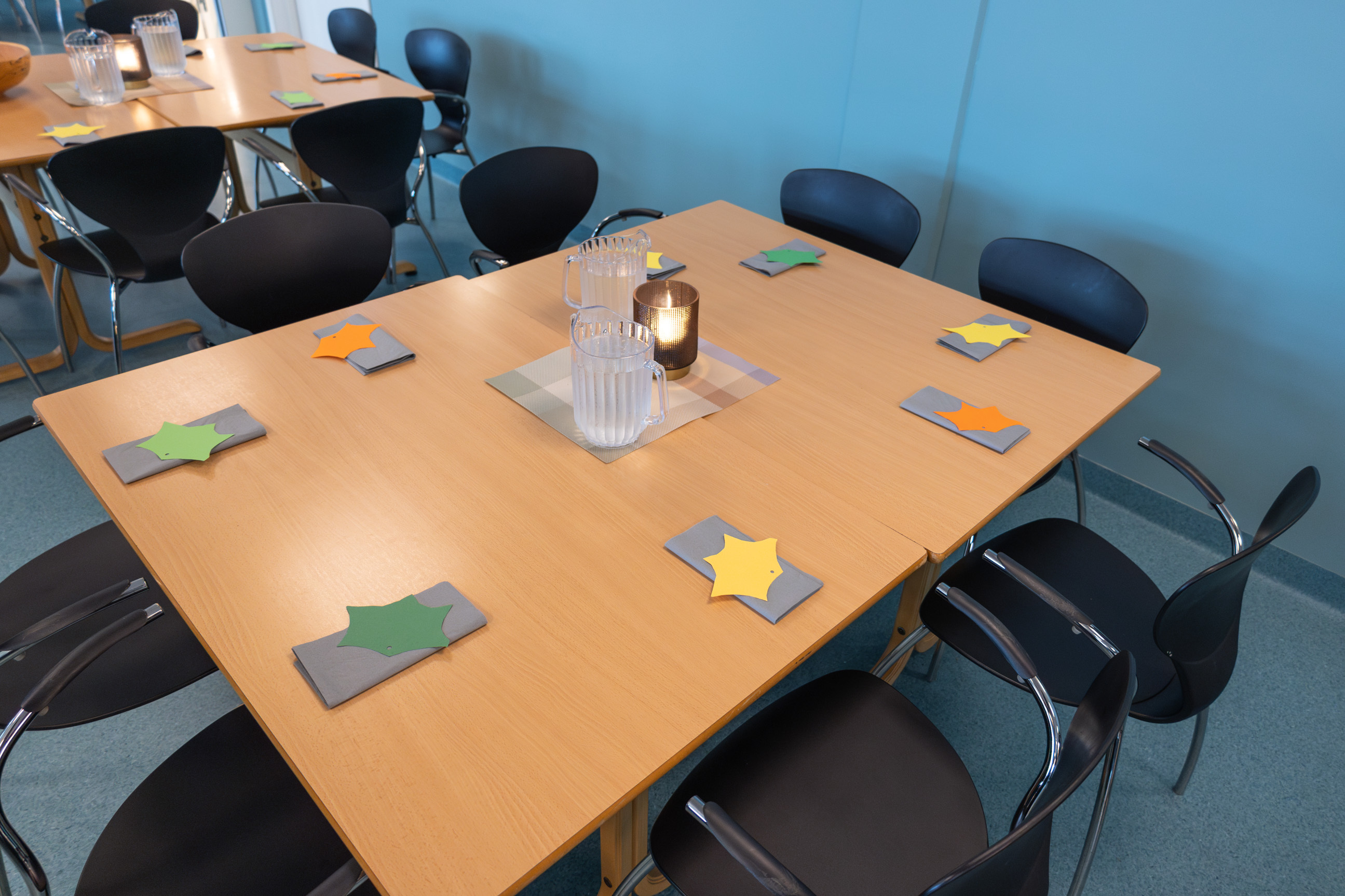 Foto: To bord på rekke pyntet med lys og servietter. På hver plass ligger et ark klippet til som et høstblad.