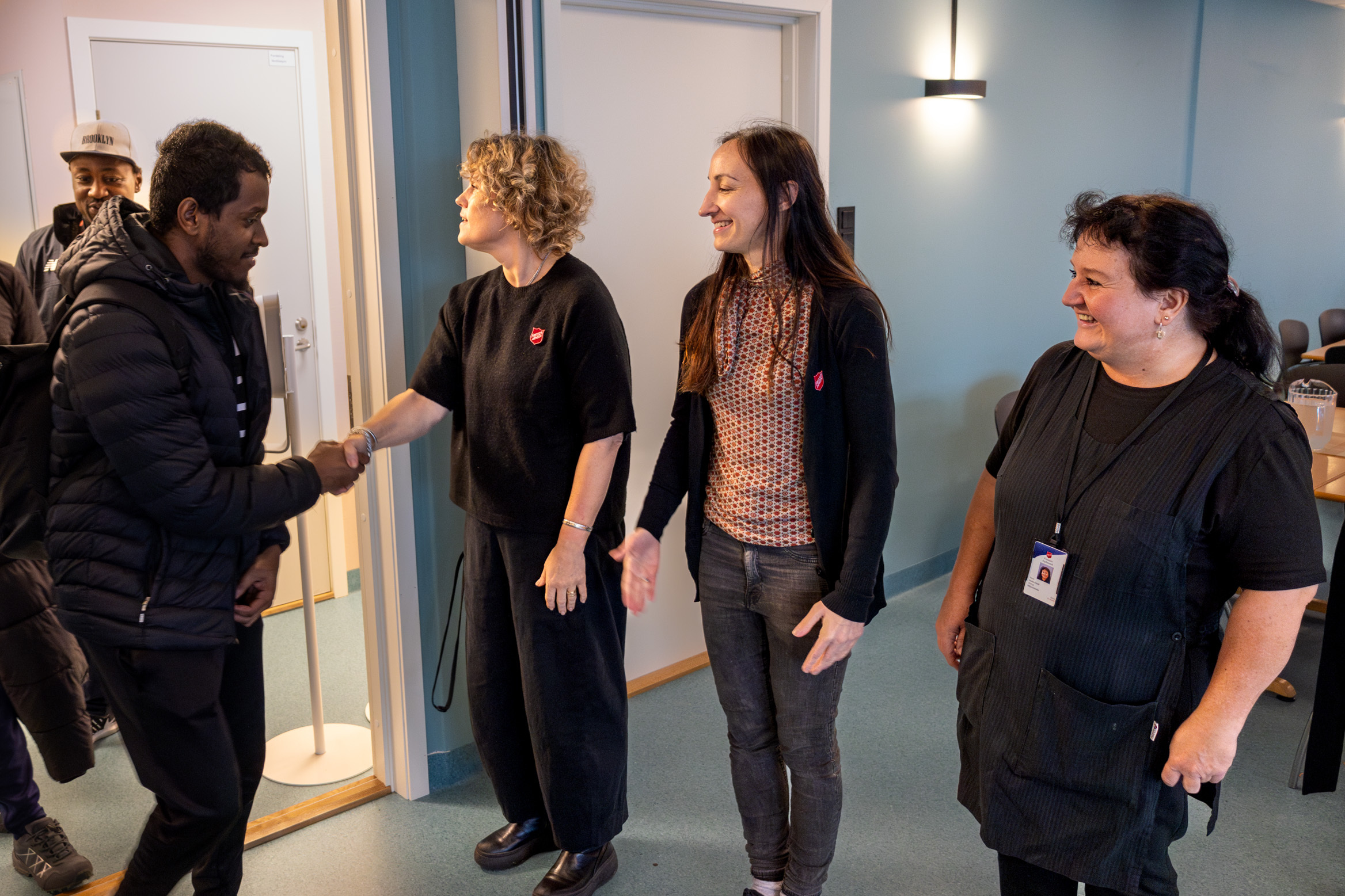 Foto: Tre kvinner står på rekke og hilser på de som kommer inn døra.