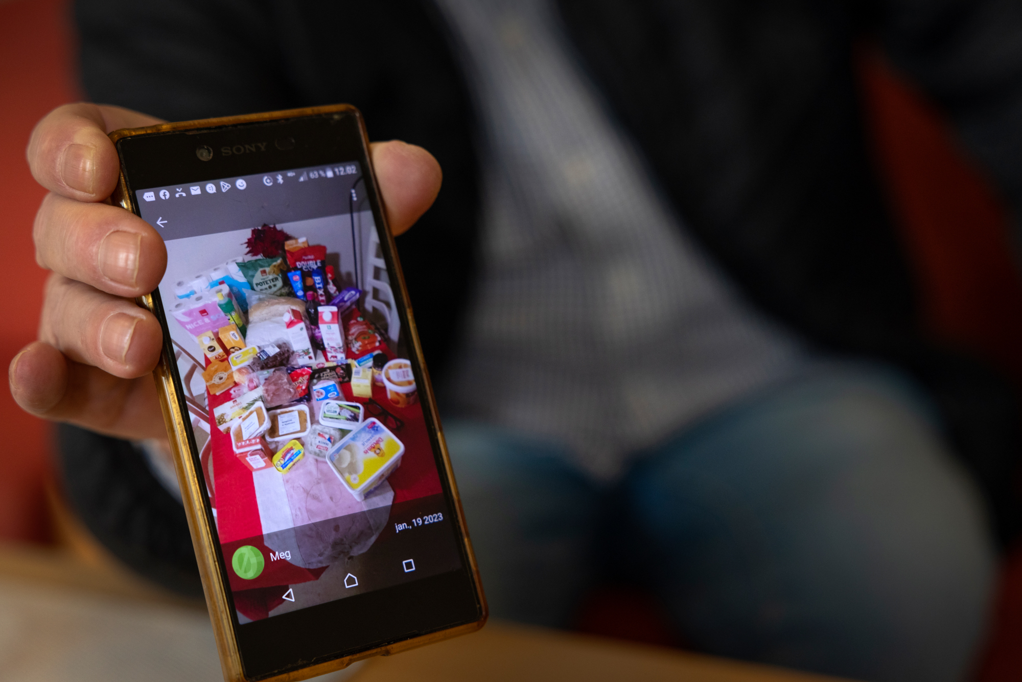 Frank viser fram bilde på mobilen hans, som viser julematen han handlet med Coop-kort som han fikk av Frelsesarmeen.