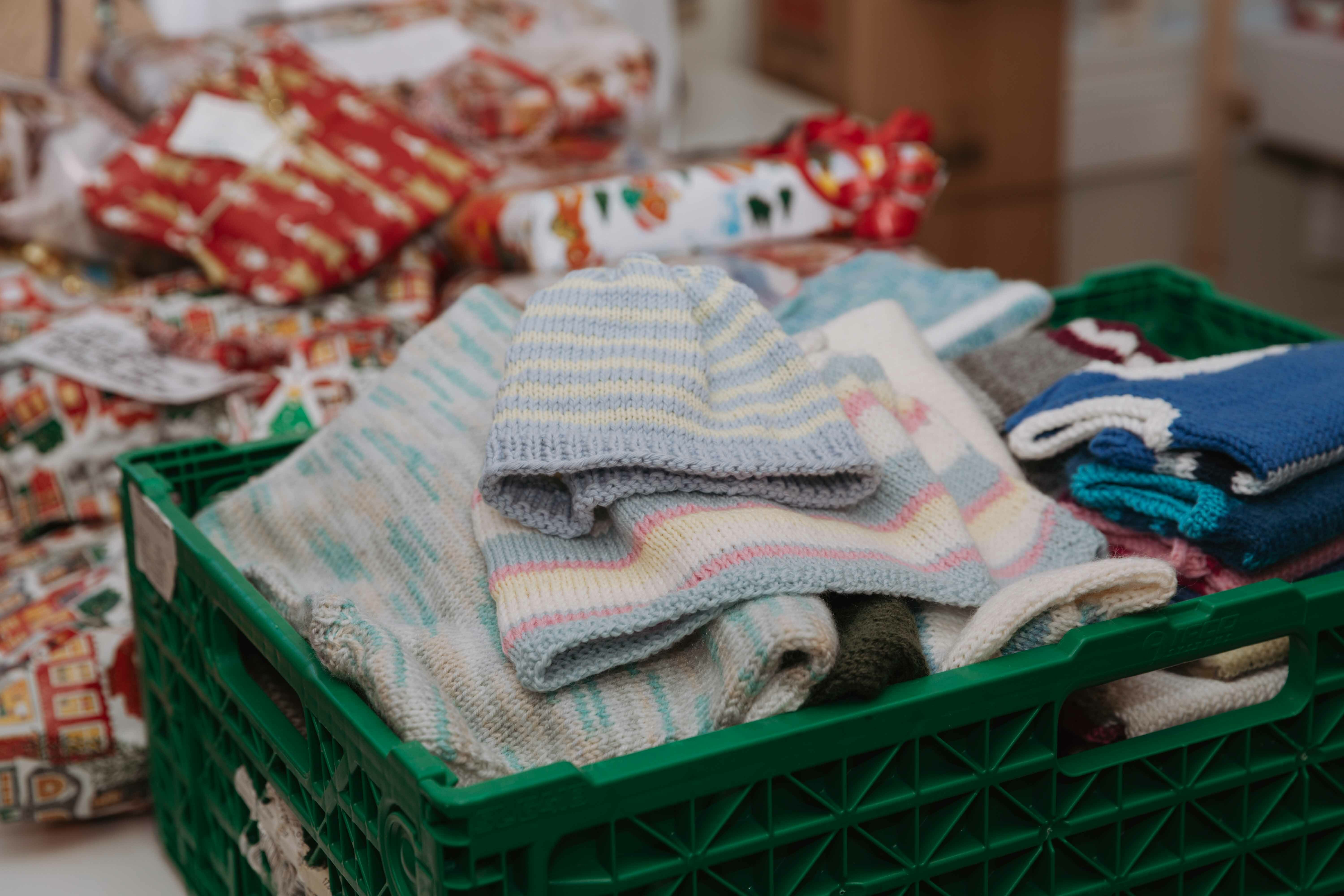 Foto: To bilder etter hverandre, der det første viser en blond dame som står med matvarer i bakgrunnen og innpakkede julegaver i en kasse foran seg. På det andre bildet vises strikkeklær som folk har laget og gitt til Frelsesarmeen.