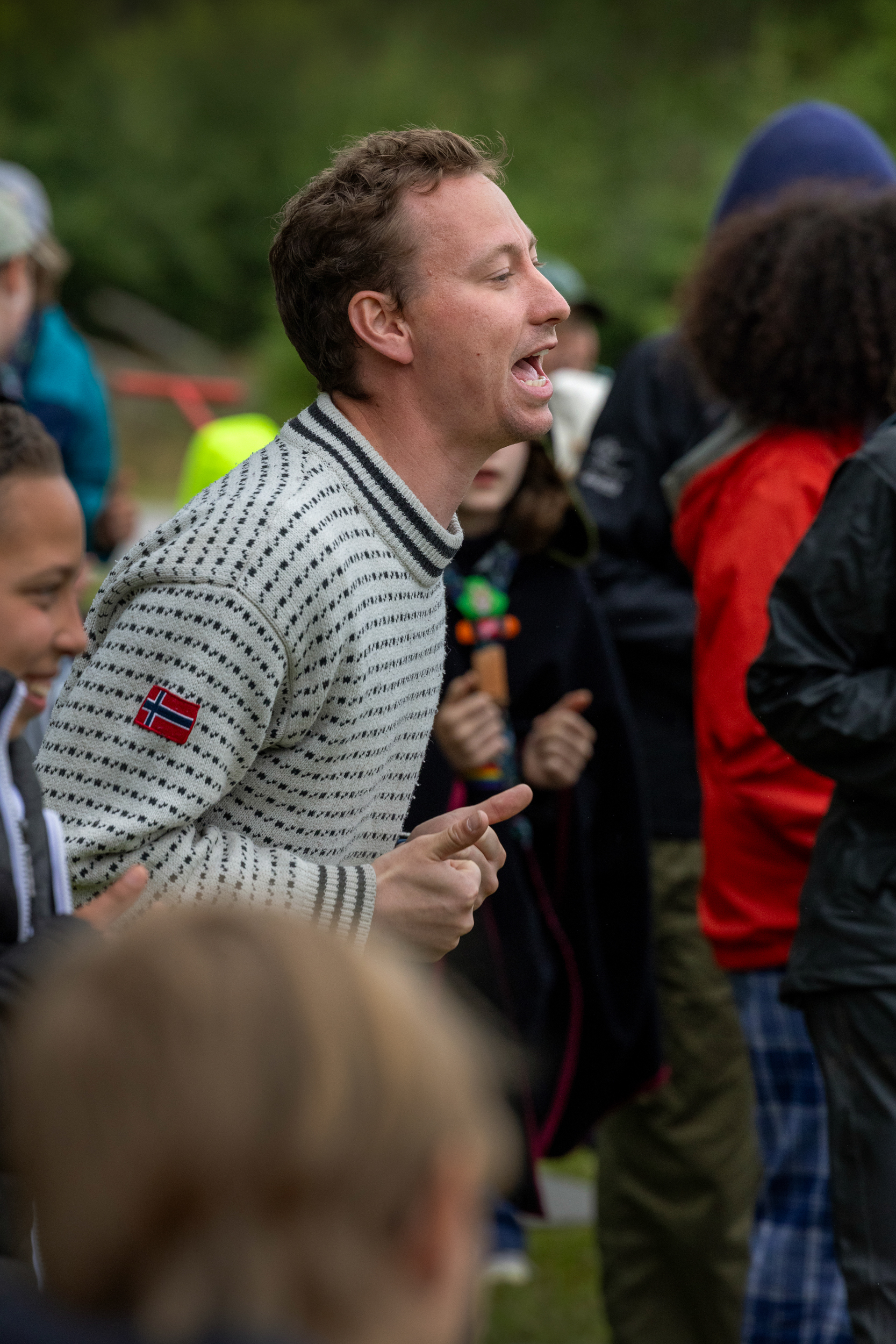 Foto: Mann i shetlandsgenser gjør seg til med grimaser foran et publikum som hermer etter ham.