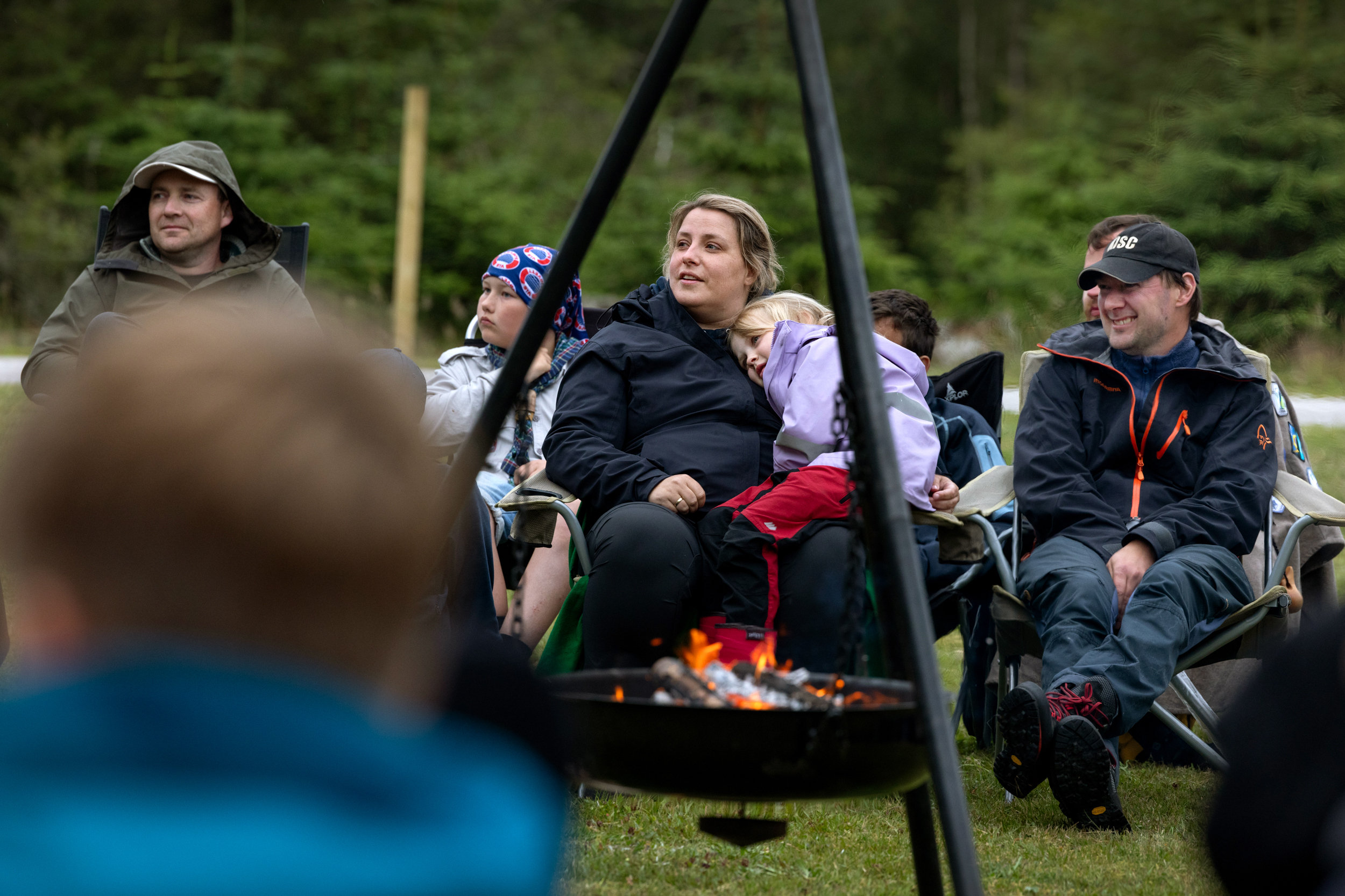 Foto: Folk sitter på rekke på den andre siden av bålpanna.
