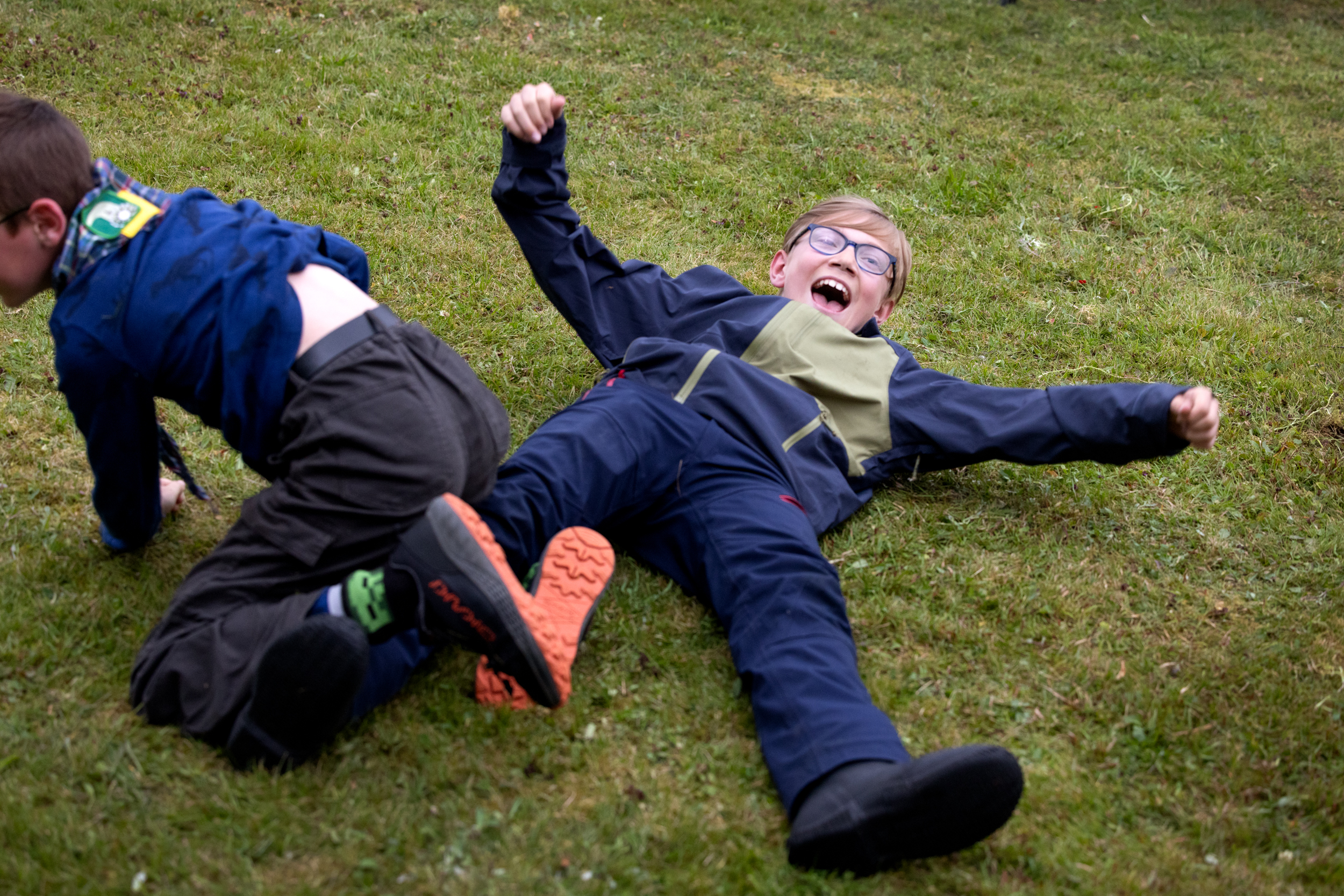 Foto: Gutt med briller og lyst hår. Han spreller med armer og bein der han ligger på bakken. En annen gutt er på vei bort fra ham.