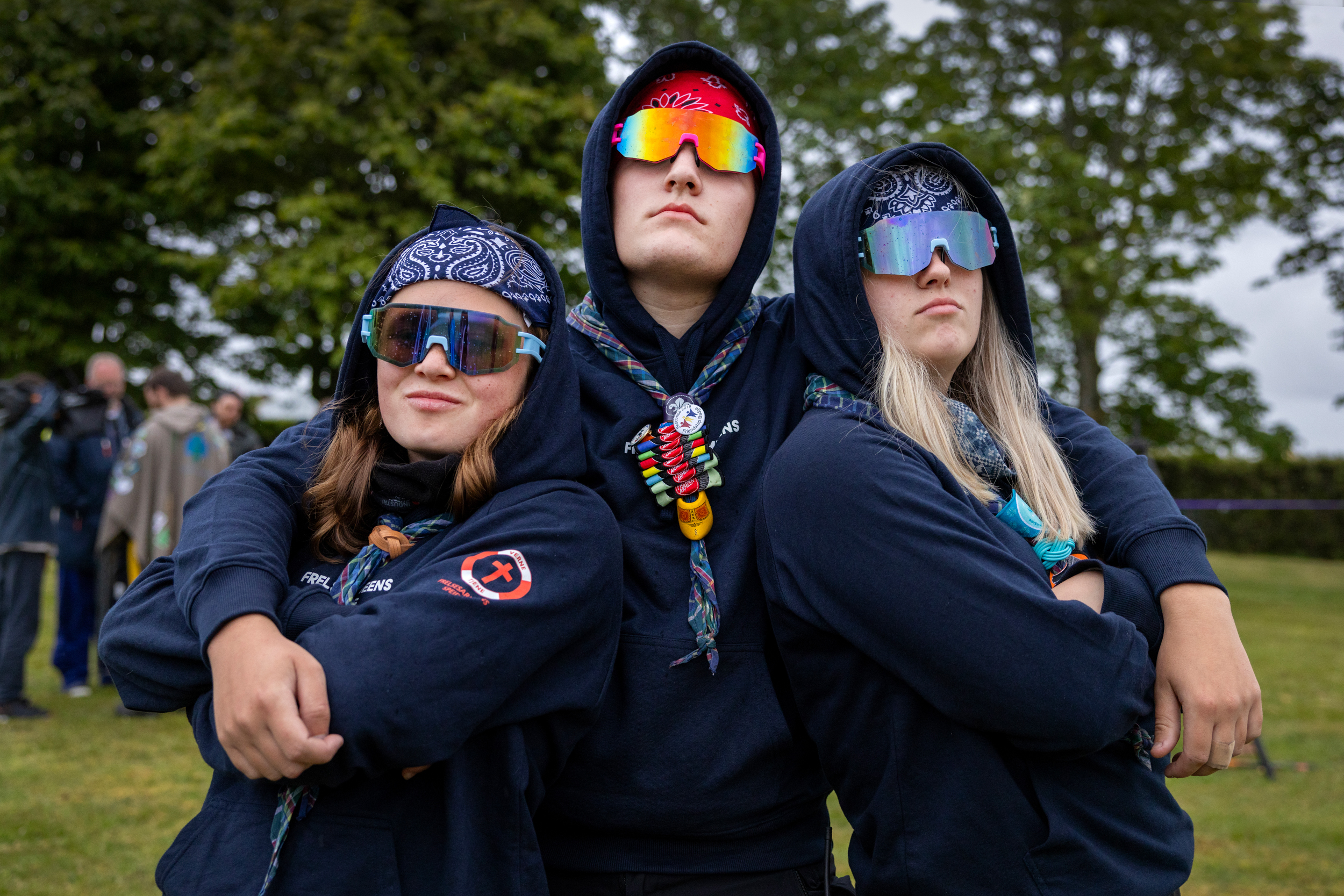 Foto: Ung mann poserer sammen med to jenter – én på hver side av seg. De har på seg marineblå hettegensere fra Frelsesarmeens speidere.