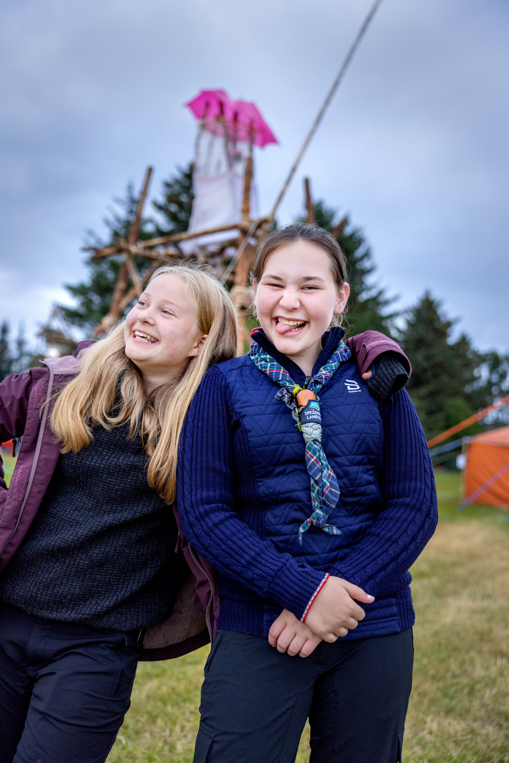Foto: To jenter, en blond og en brunhåret, gjør grimaser til fotografen. Bak ses samme fyrtårn som i bildet øverst i saken.