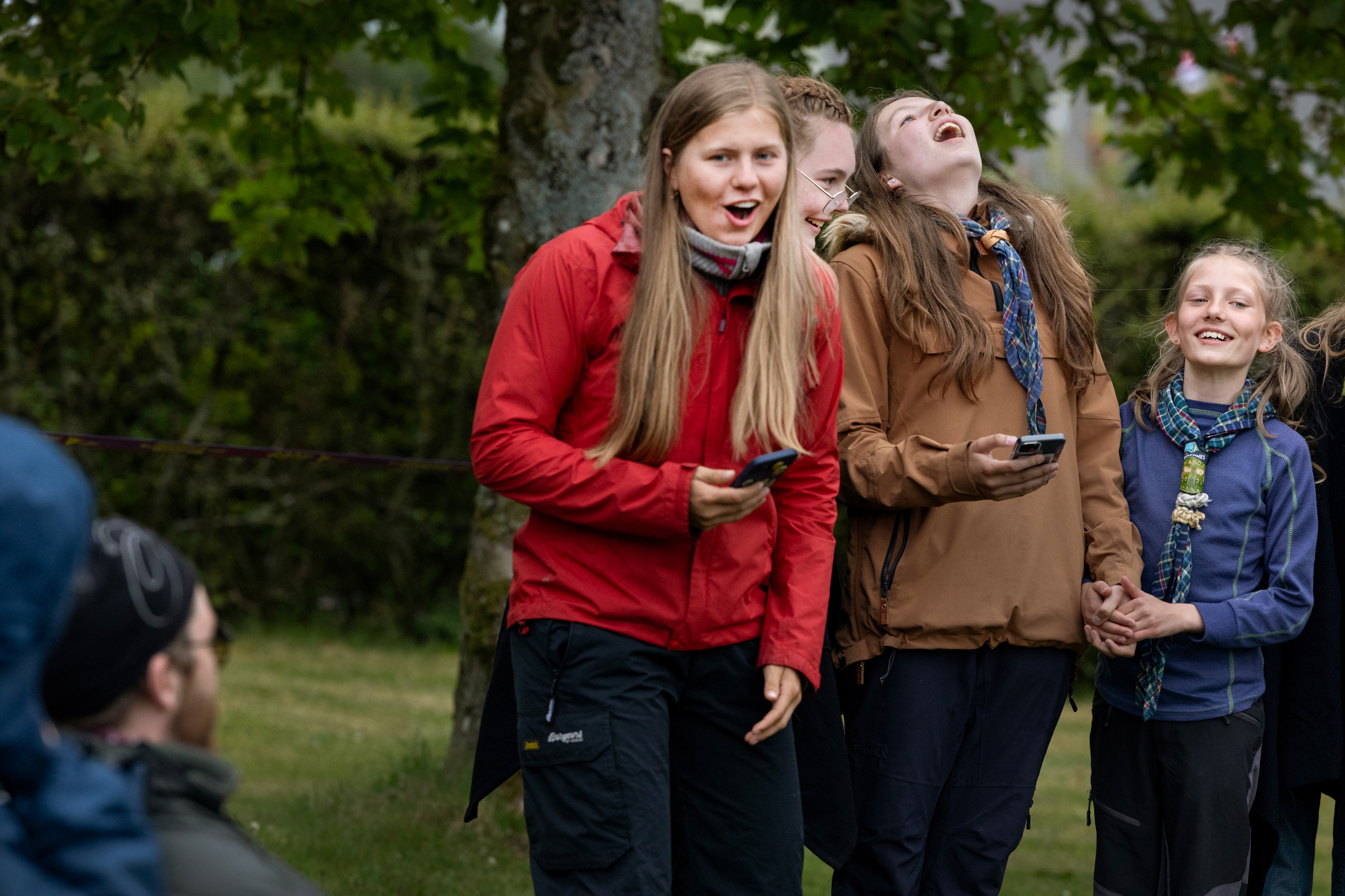 Foto: Et kor på fire jenter i ulike alder som synger. De leser teksten fra mobilen.