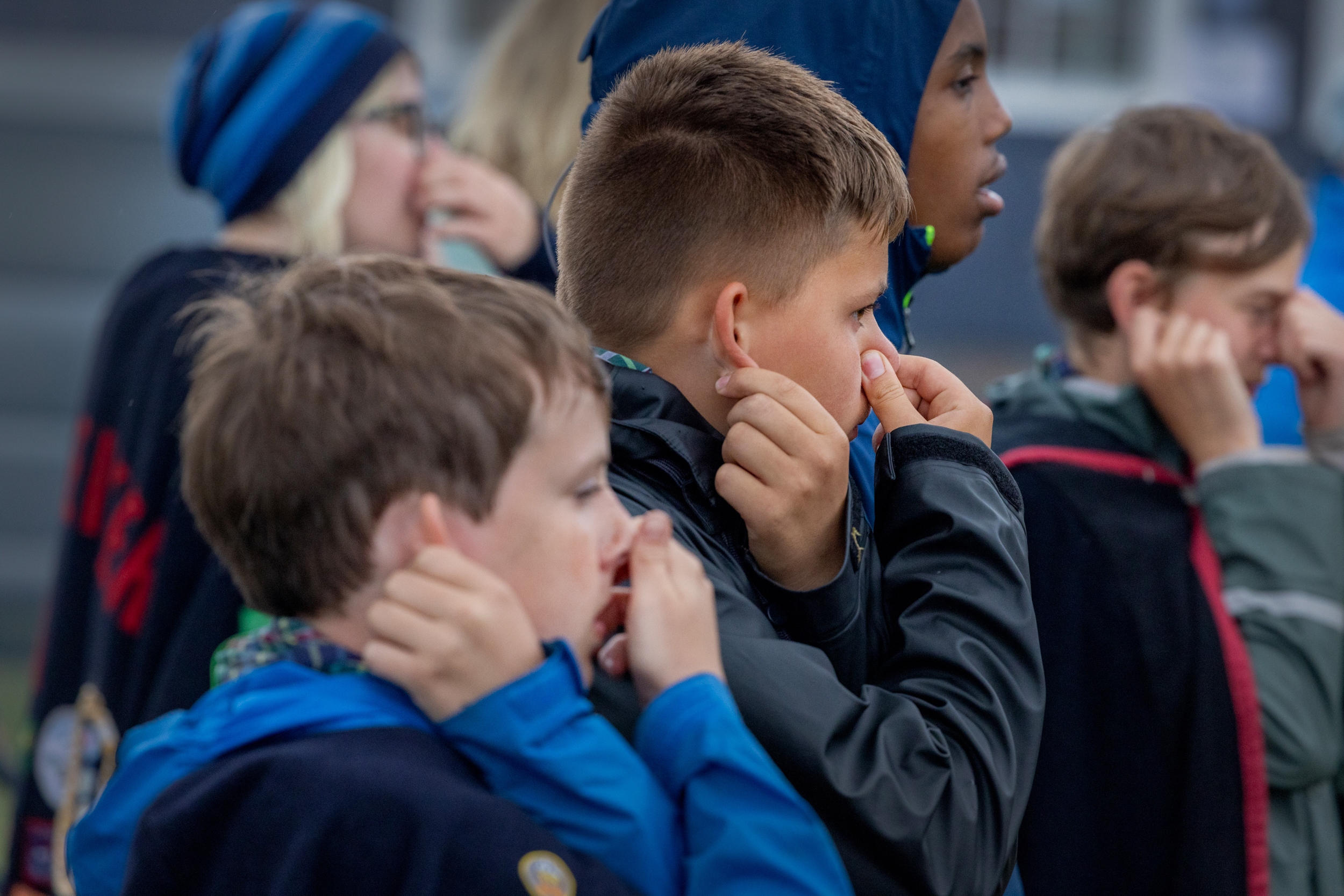 Foto: Flere barn i regntøy holder på neser og ører.