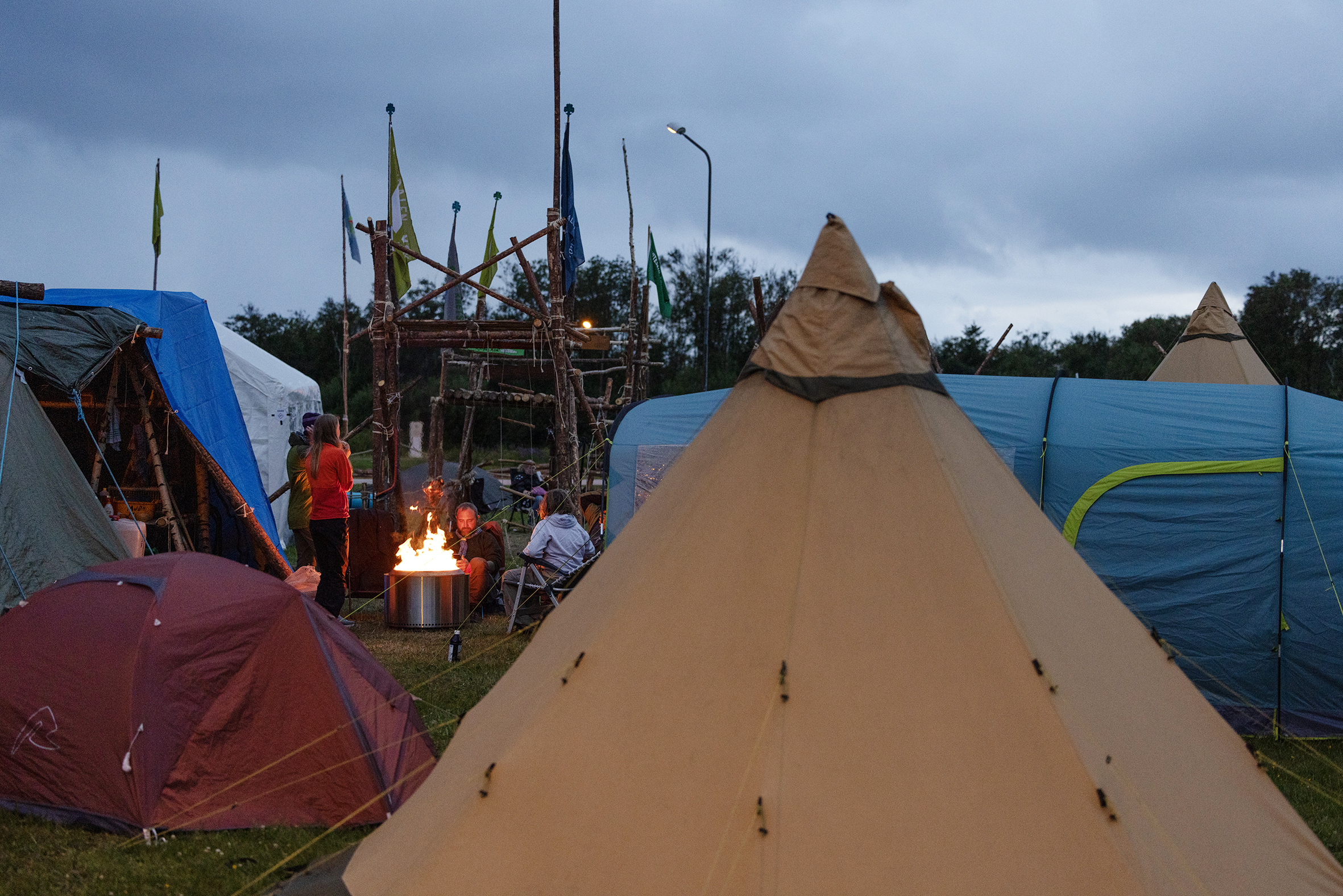 Foto: Oversiktsbilde av flere telt og annet byggverk. Ild midt i bildet med noen mennesker rundt.