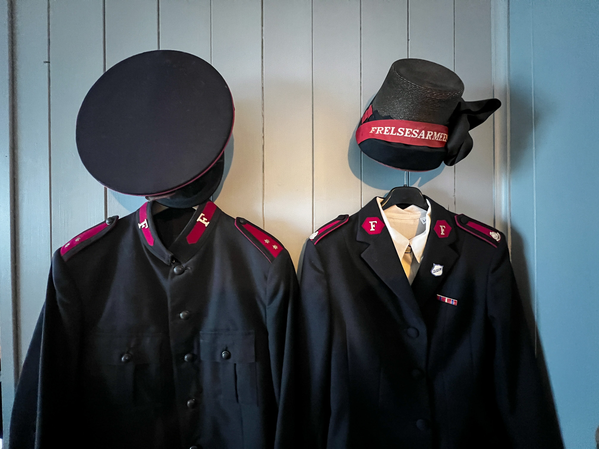 Nærbilde av to uniformsjakker med hatter – til mann og kvinne.