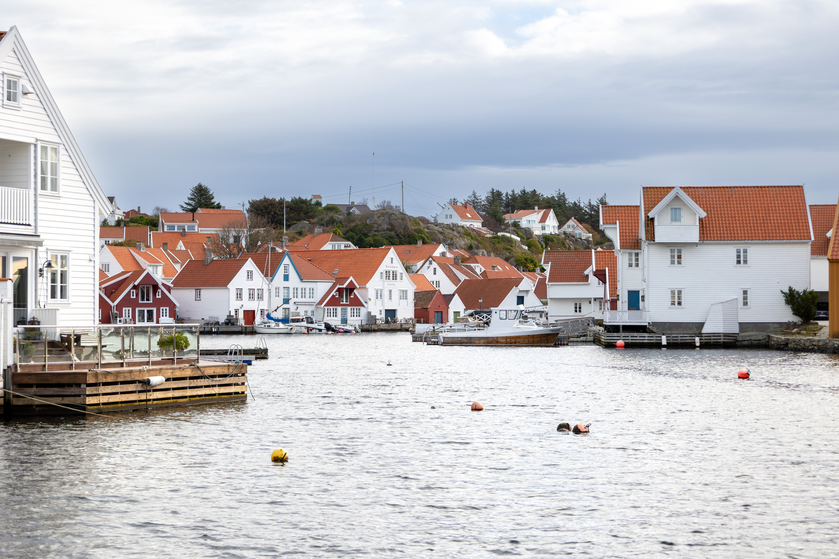Hvite hus og sjøhus bygget helt utpå kaikantene i en liten havn.