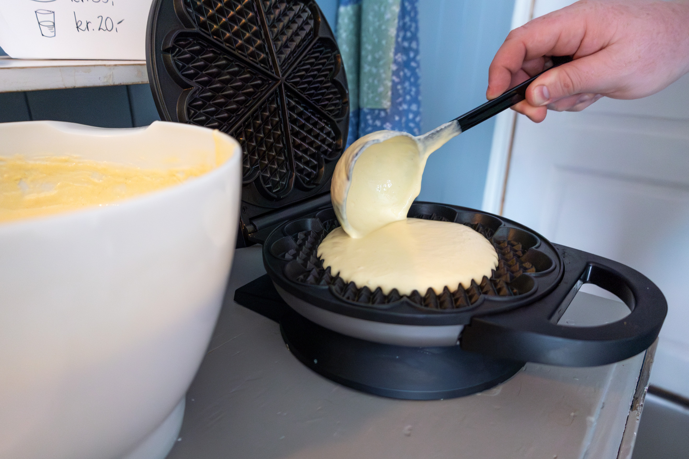 Nærbilde av vaffelrøre som smøres ut over jernet.