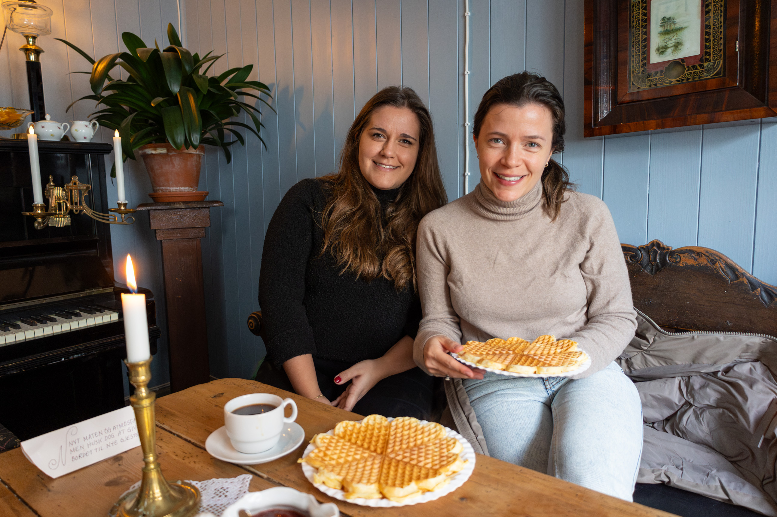 To bilder ved siden av hverandre der vi først ser to unge kvinner som ligner på hverandre i en sofa, deretter er det nærbilde av en av dem som river opp et vaffelhjerte på tallerken.