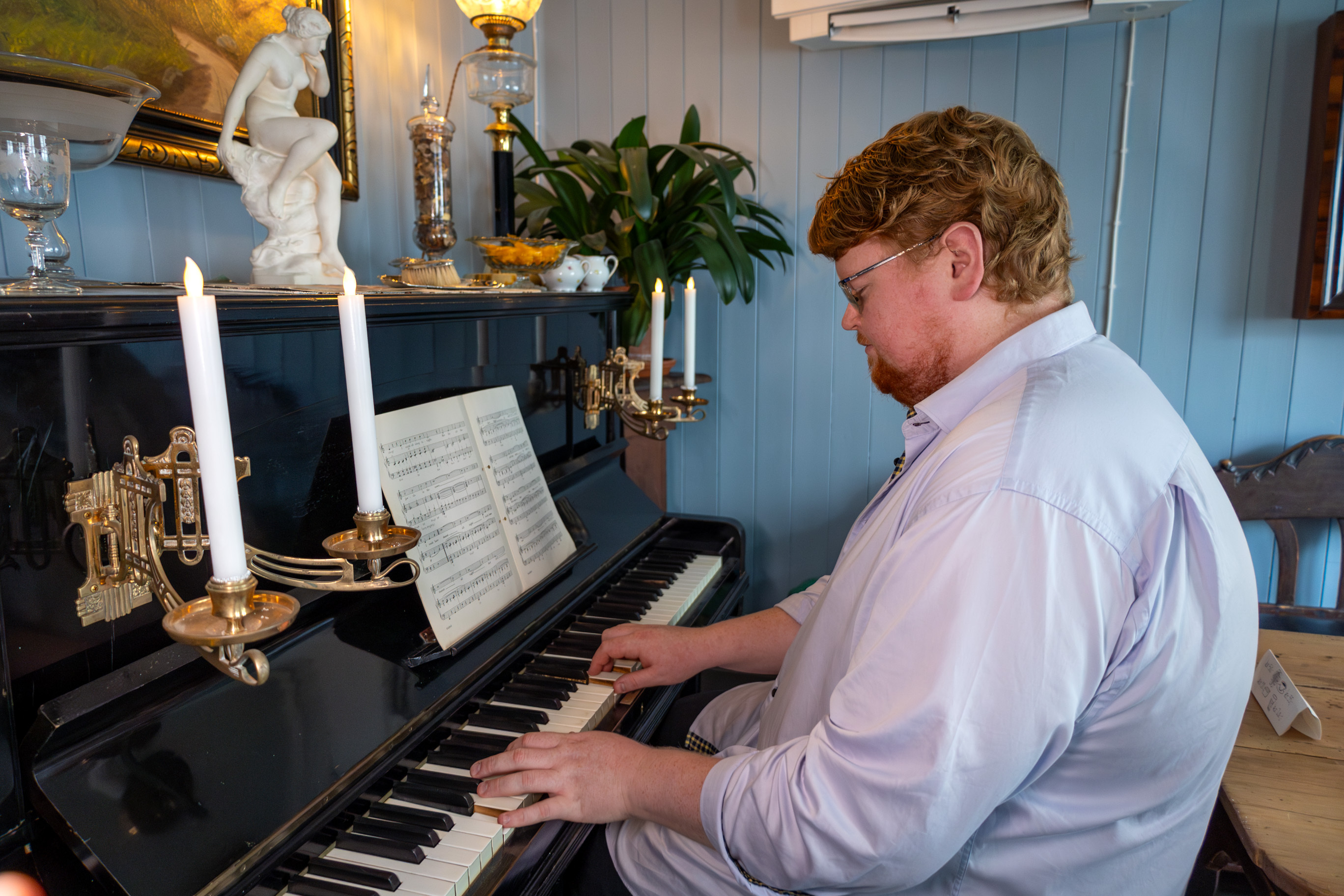 Mann sitter ved et gammelt piano og spiller.