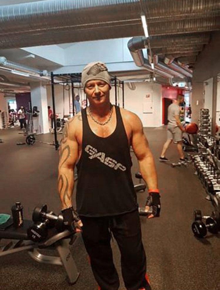Foto: Mann med store muskler poserer inne i et treningsstudio.