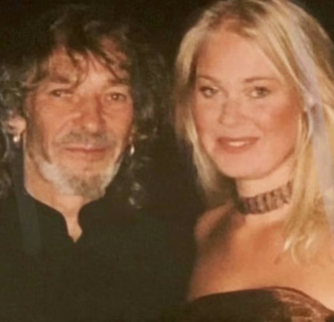 Foto: Fra 90-tallet av en mann i 50-årene med halvlangt, mørkt hår og ringer i begge ørene. Han står sammen med en blond og fager ung jente i en stoppeløs kjole og choker rundt halsen.