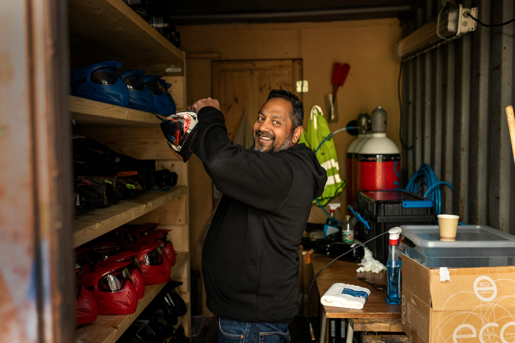 FOto: Mann som står inne et lagringskur for paintballutstyr og hjelmer.