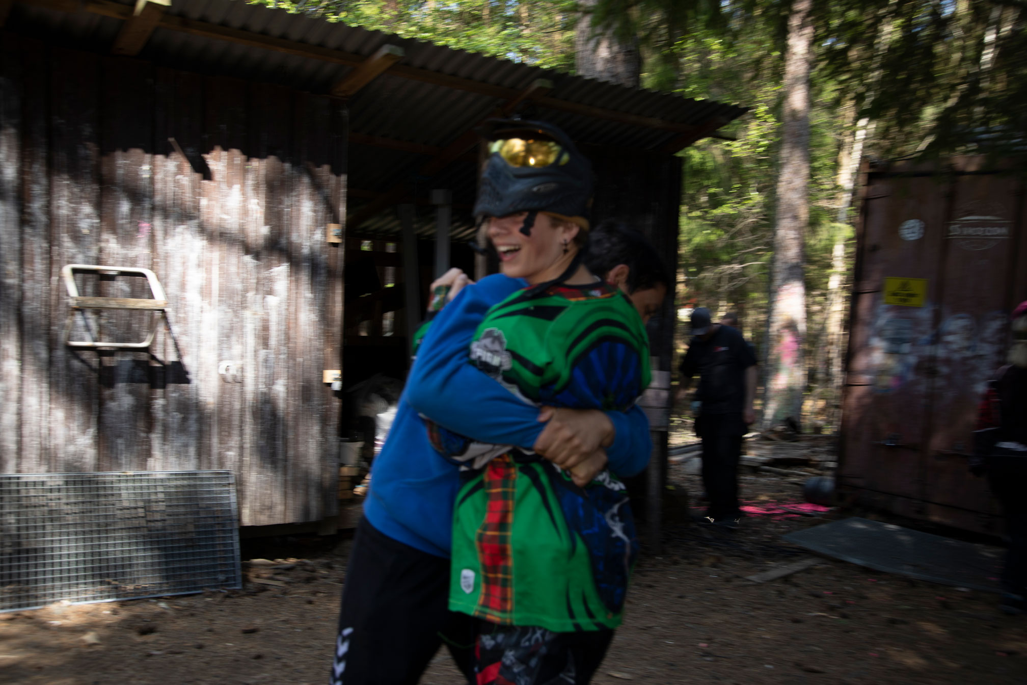 To personer med hjelmer og paintballutstyr som klammer hverandre.