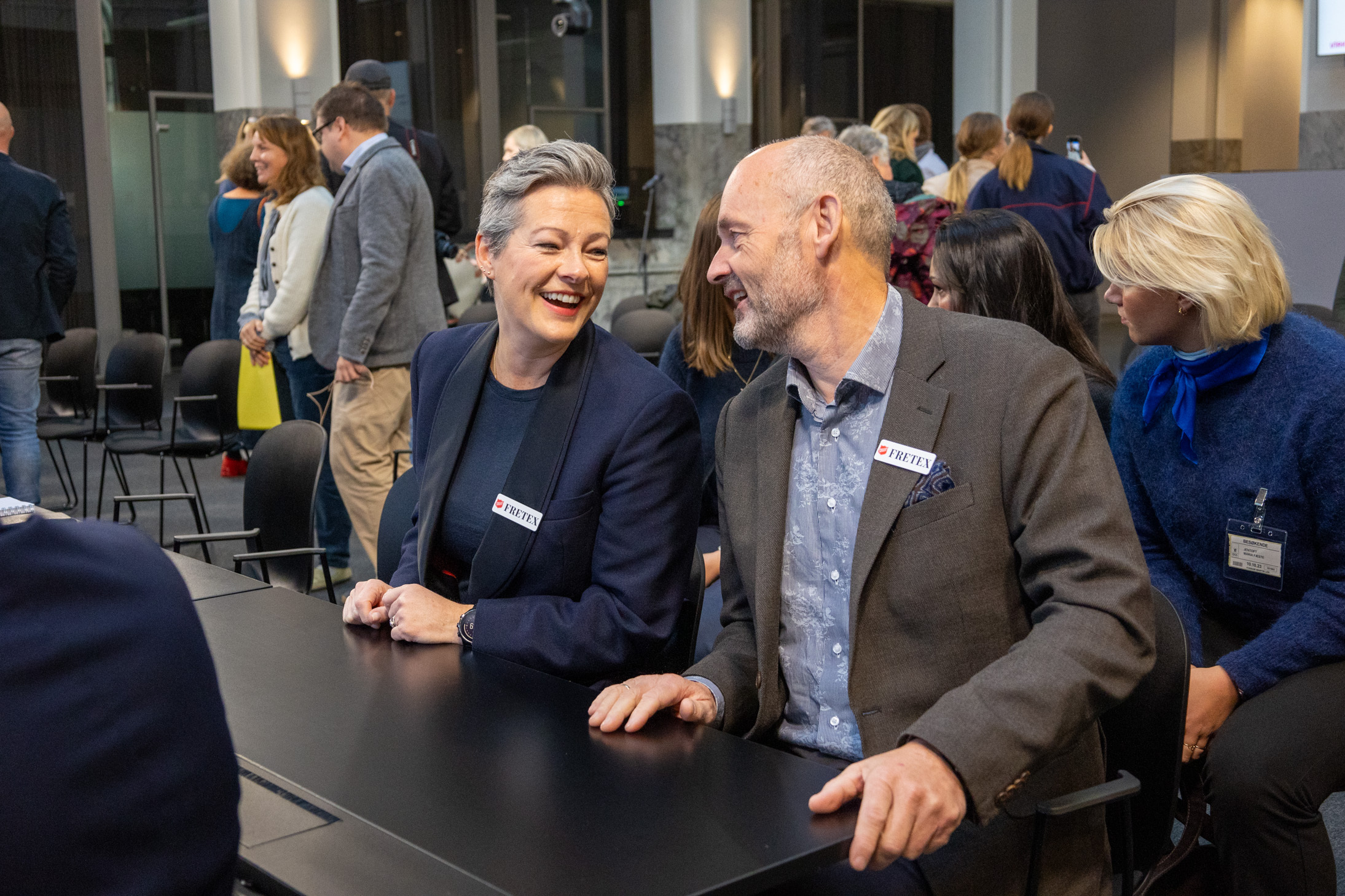 Mann og kvinne som sitter ved et bord. Ler og smiler til hverandre.