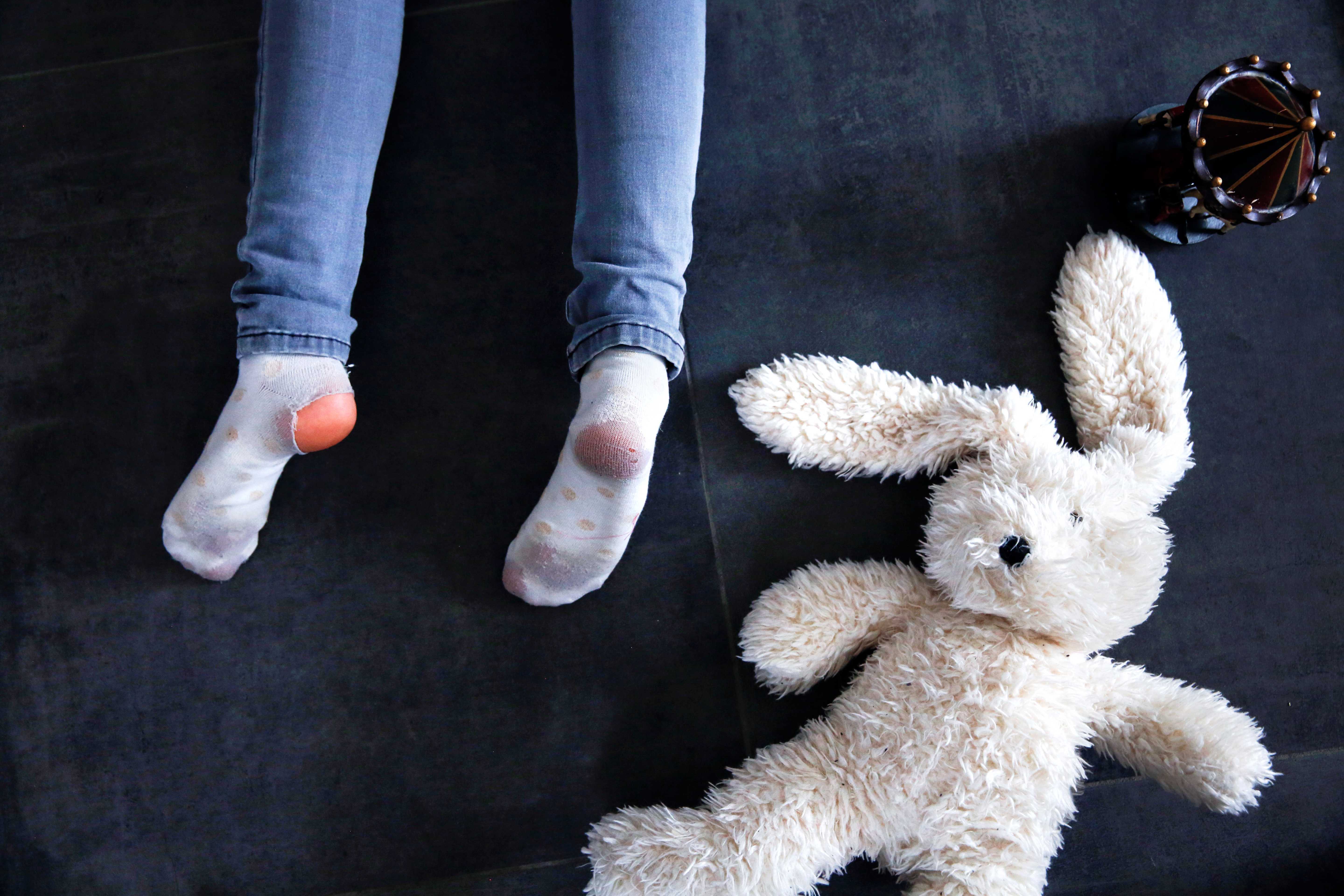 Barneføtter med slitte sokker og et slitt kosedyr