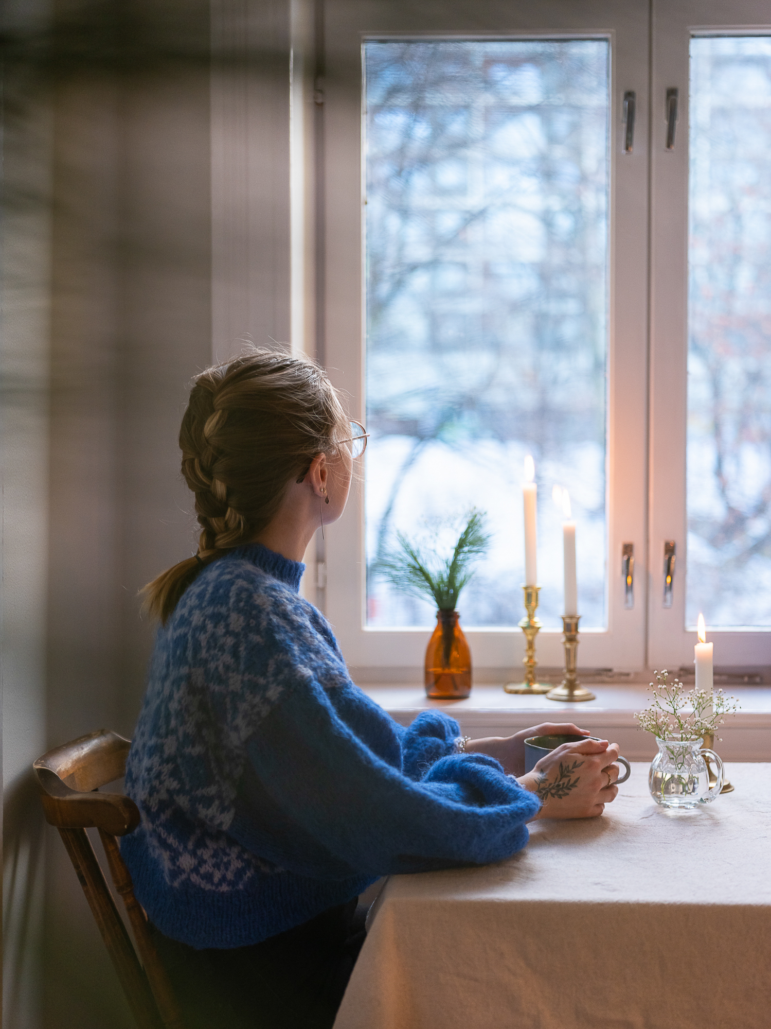 kvinne sitter med ryggen til og ser ut vindu