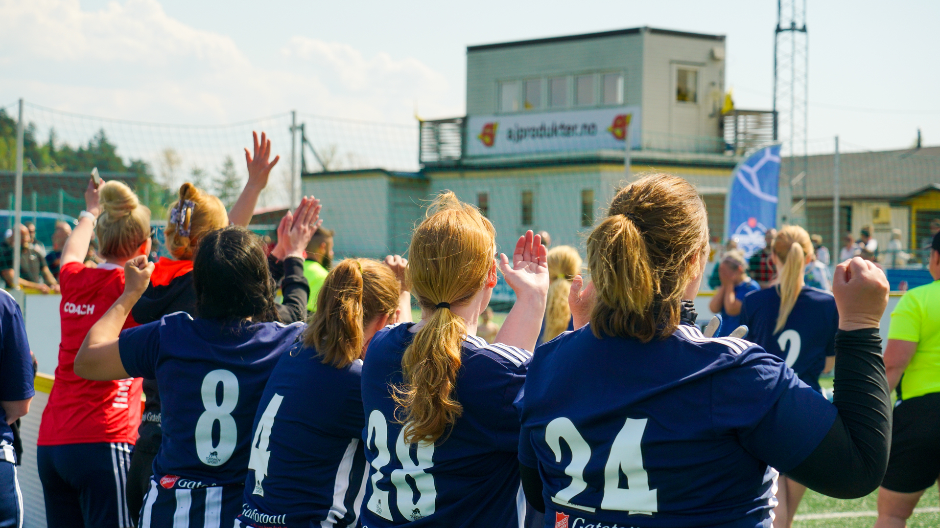 Damer i fotballdrakter står langs vantet og ser på kampen. Foto: Mattias Amland
