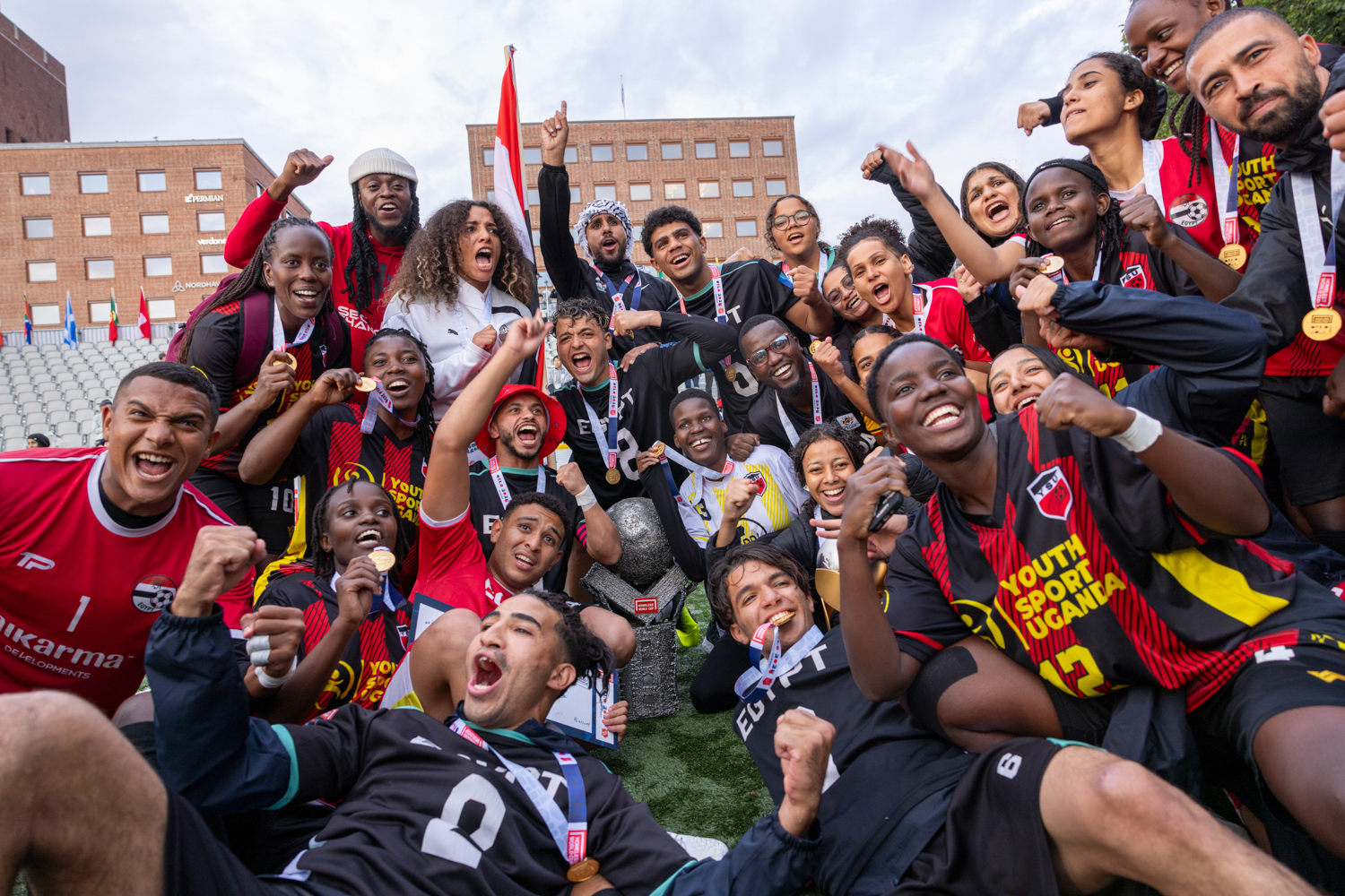 Foto: Tnternasjonale fotballag – kvinner og menn – jubler på en liten gressbane foran Rådhuset i Oslo.