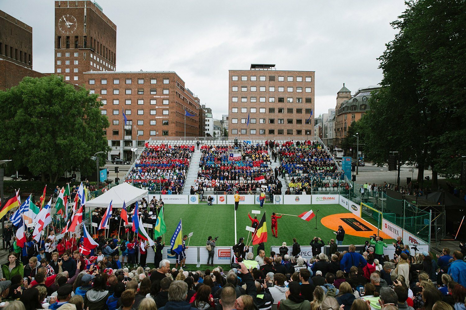 Bilde av en fotballbane med fulle tribuner rett foran Rådhuset i Oslo.