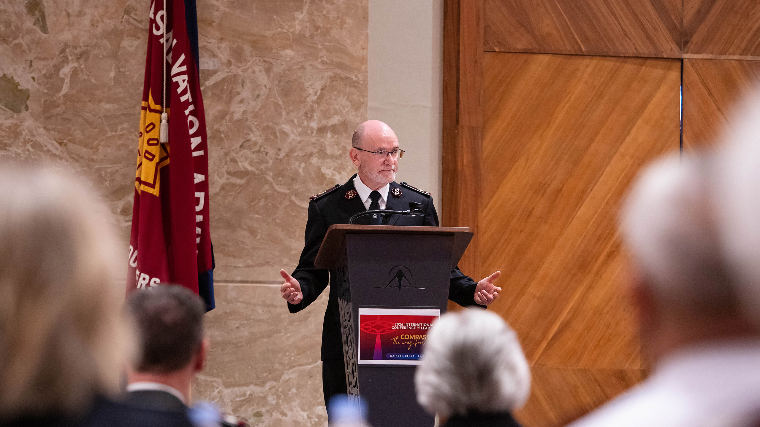 General i Frelsesarmeen, Lyndon Buckingham på talerstolen i konferansesal i Nairobi, Frelsesarmeens flagg ved siden