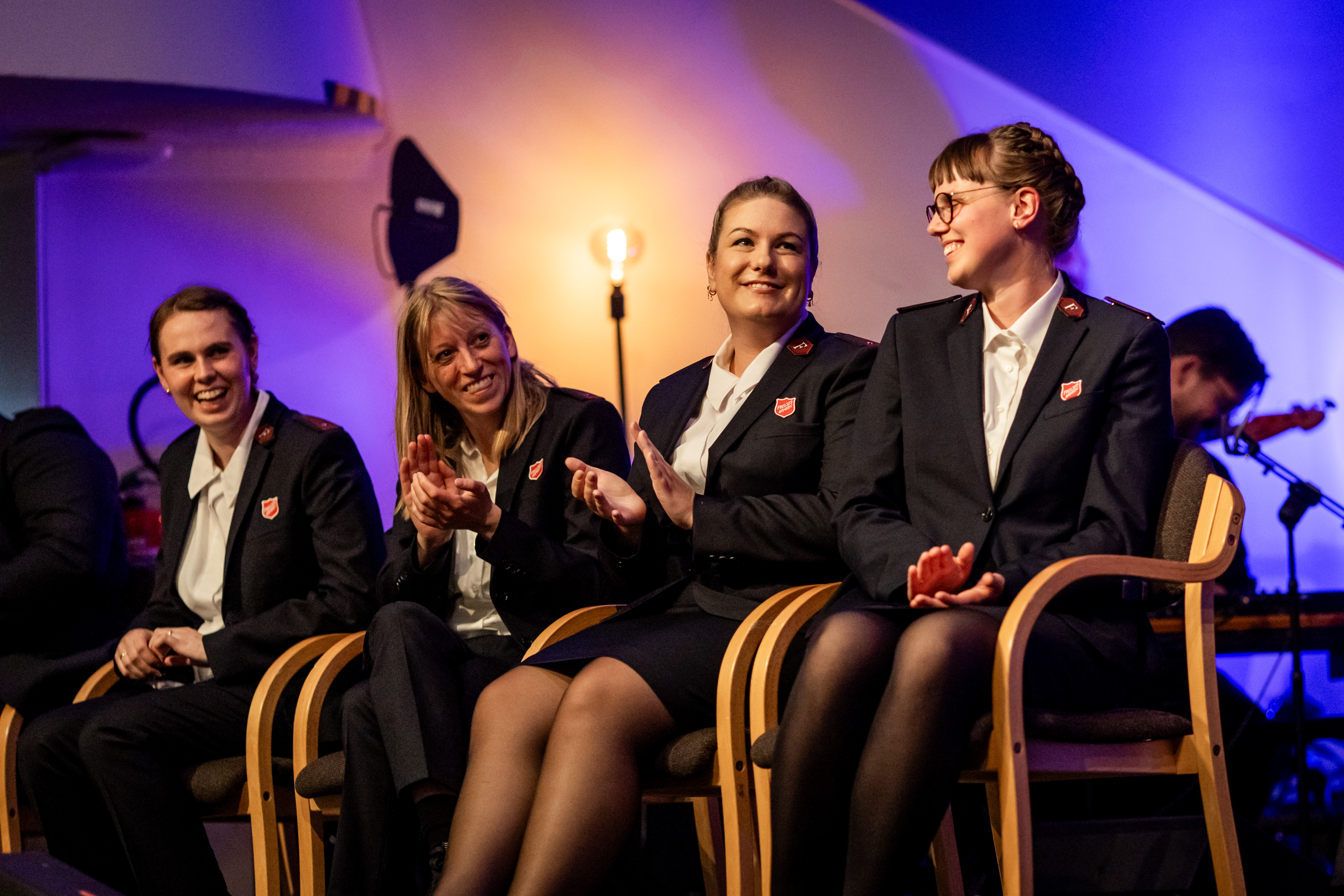 Fire nylig utnevnte løytnanter i Frelsesarmeens tjeneste sitter på stoler på en scene oi Misjonssalen: Moira, Tonje, Christine og Emilie.
