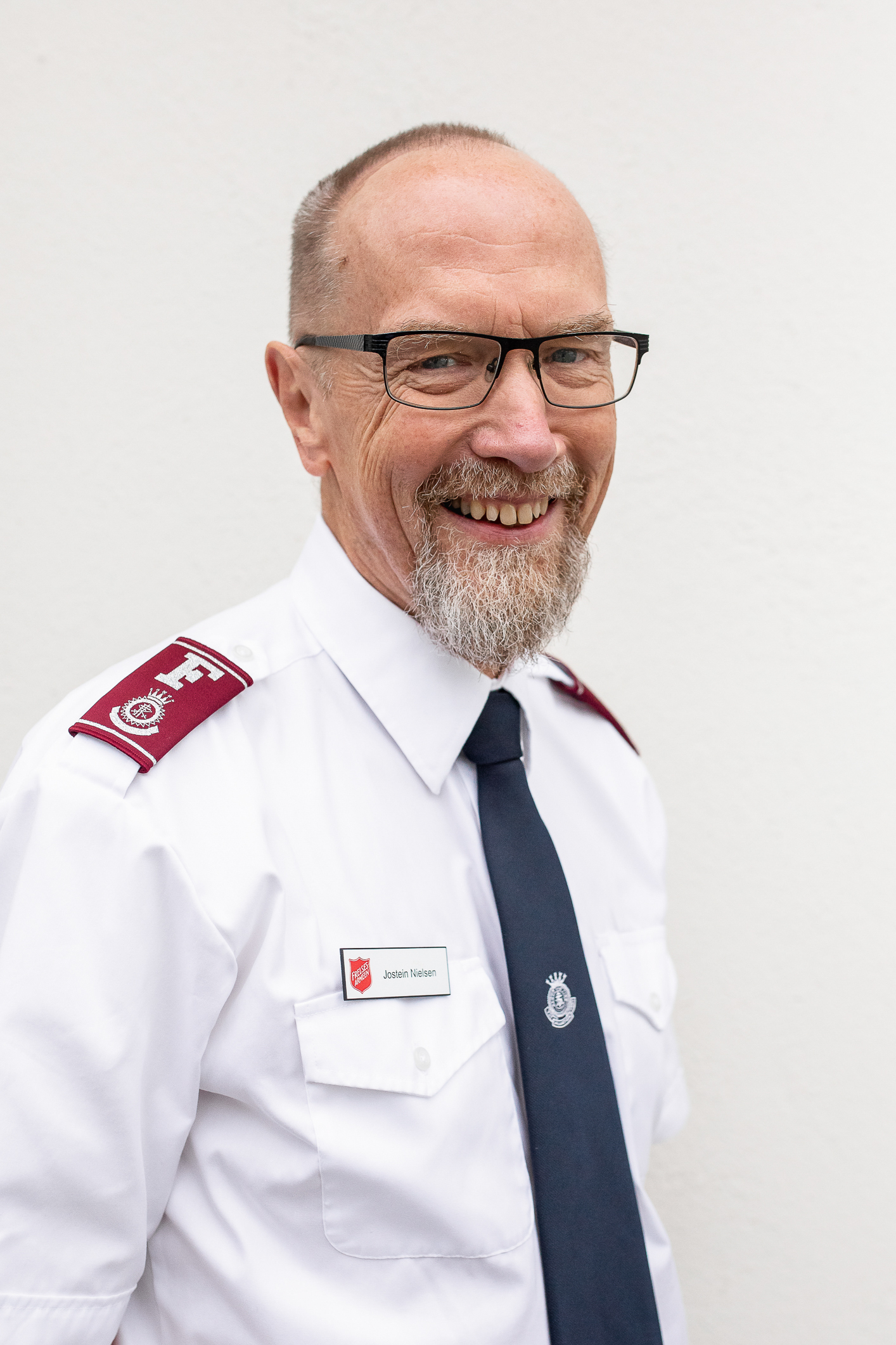 Skallet eldre mann med briller med Frelsesarmeens hvite skjorte og mørke slips