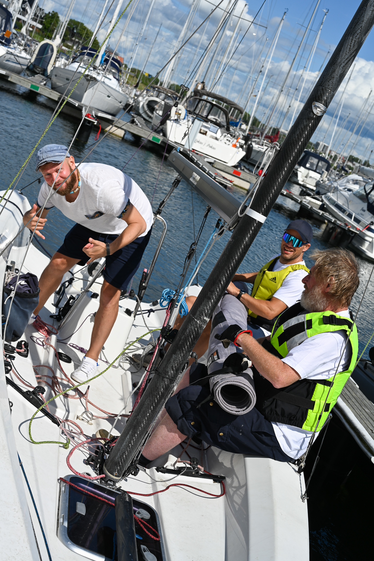 Tre menn i en seilbåt. De pakker sammen for dagen.