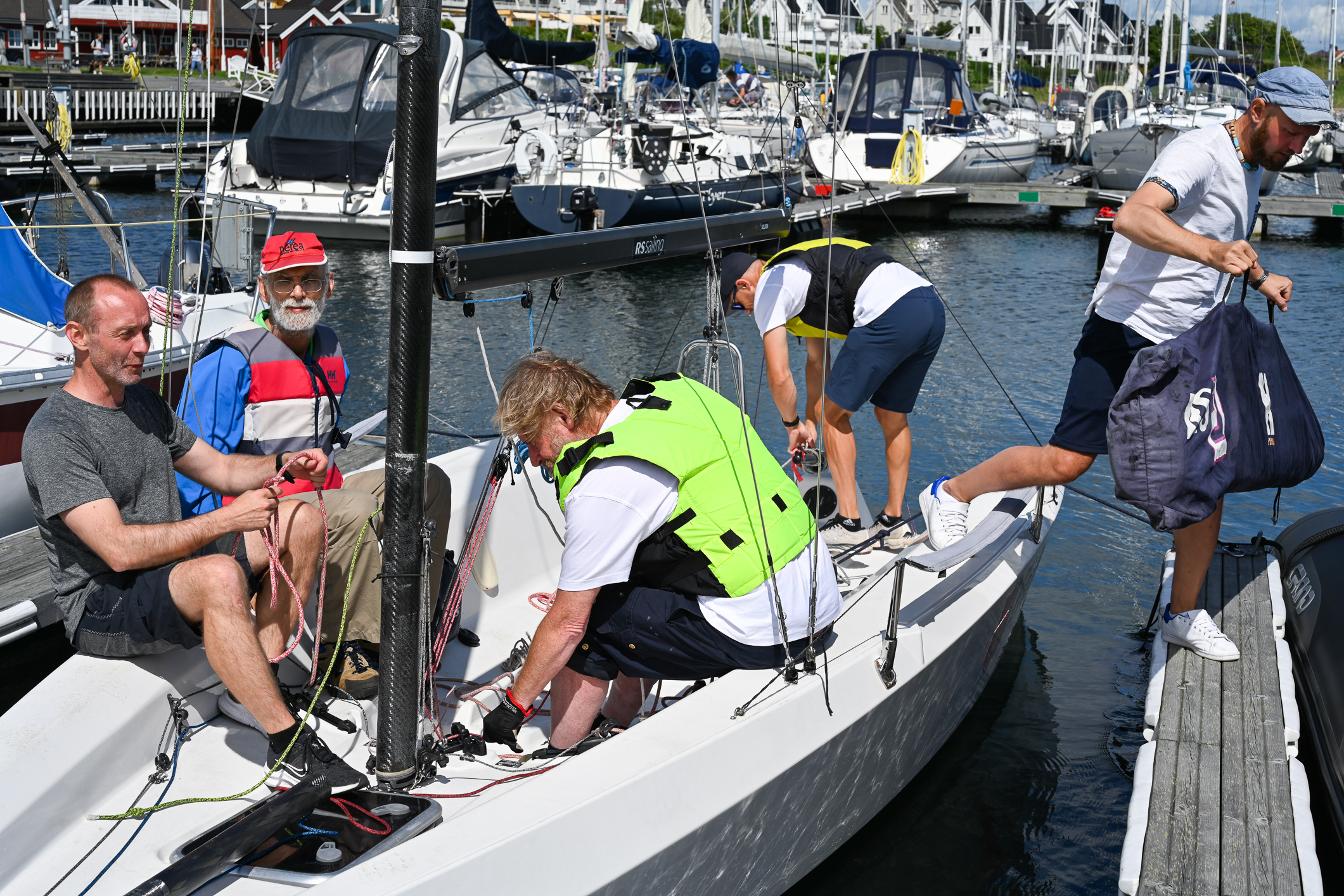 Fire menn i en båt. En femte er på vei i land.