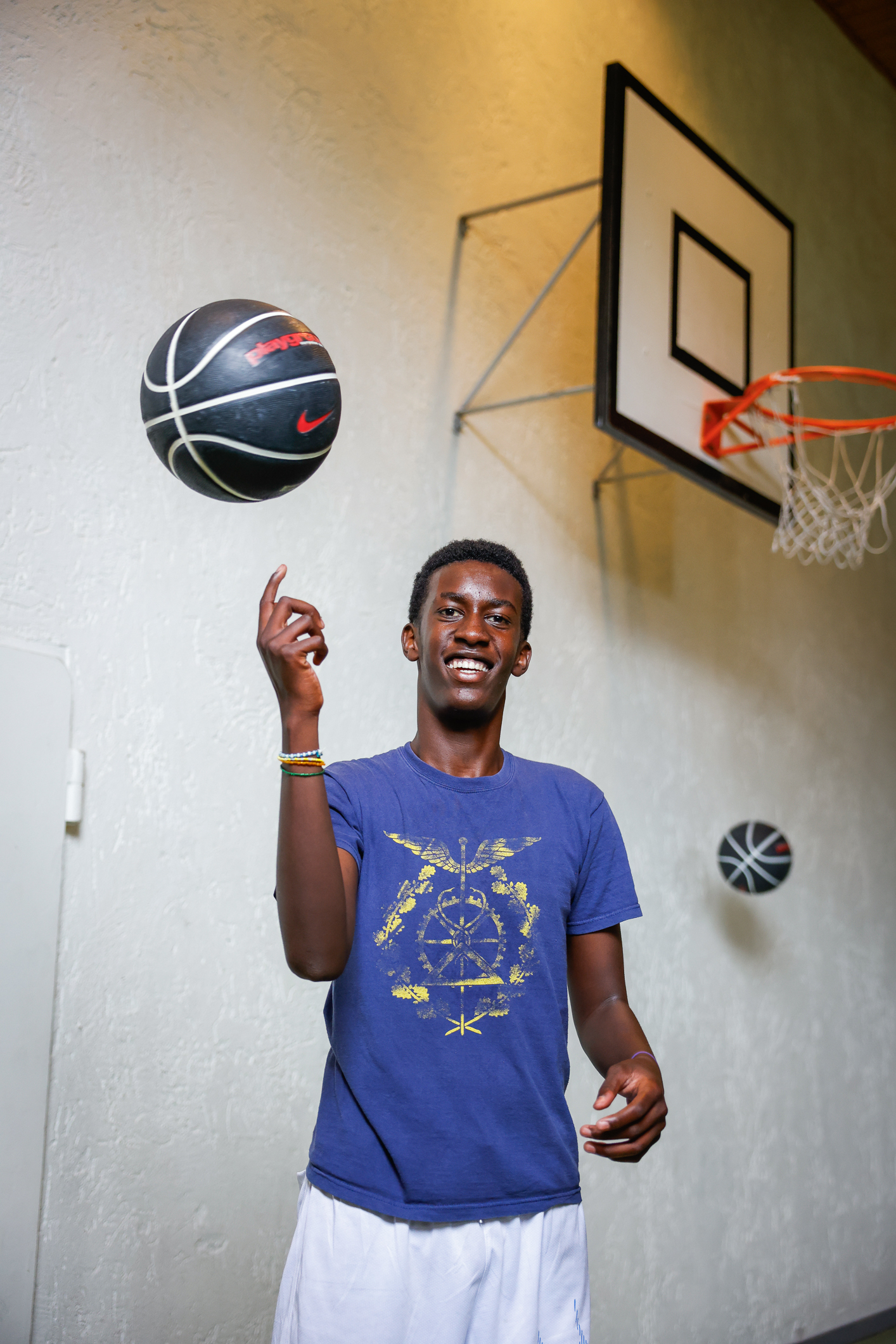 Ung gutt som snurrer basketball med fingeren inne i en gymsal.